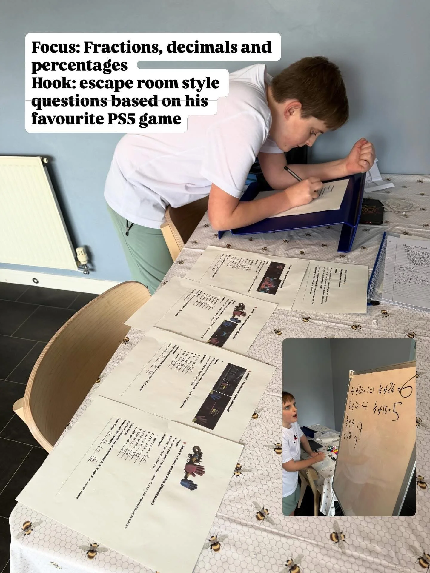 A boy is leaning over a table, working on a tablet or laptop, with papers and a whiteboard nearby. The table is covered with various papers, some with text and images, and the background shows a plain wall and a heater.