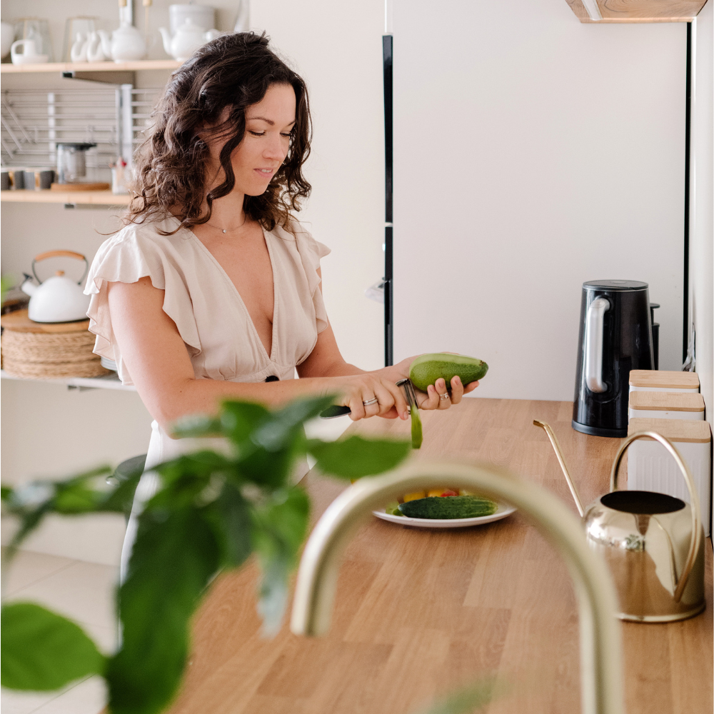 Woman peeling a cucumber in a modern kitchen.