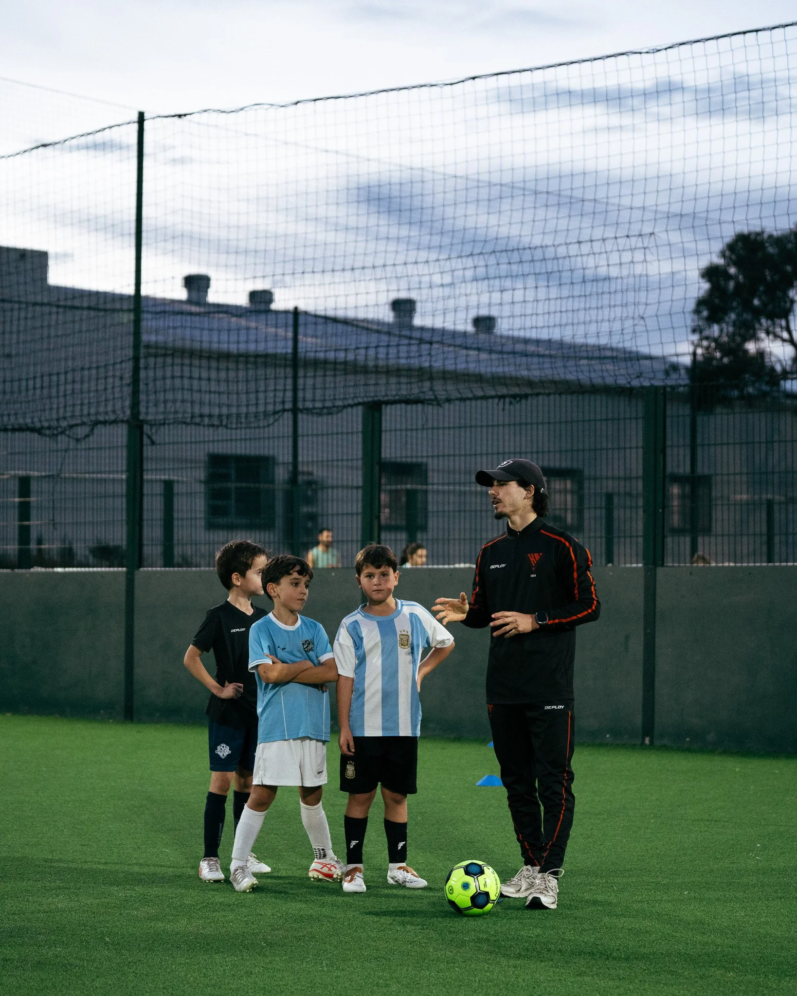 KB Football Academy coach providing instruction to players during a small-group football training session.