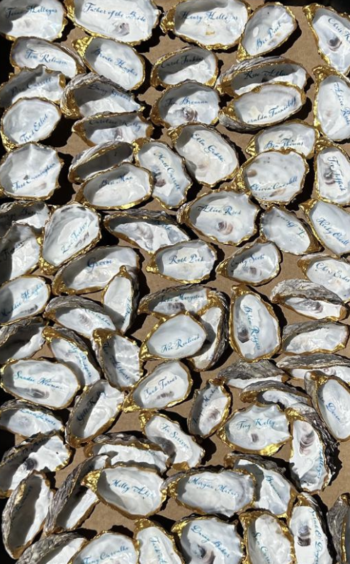 Collection of individually wrapped candies with names written inside the wrappers, decorated with gold edges.