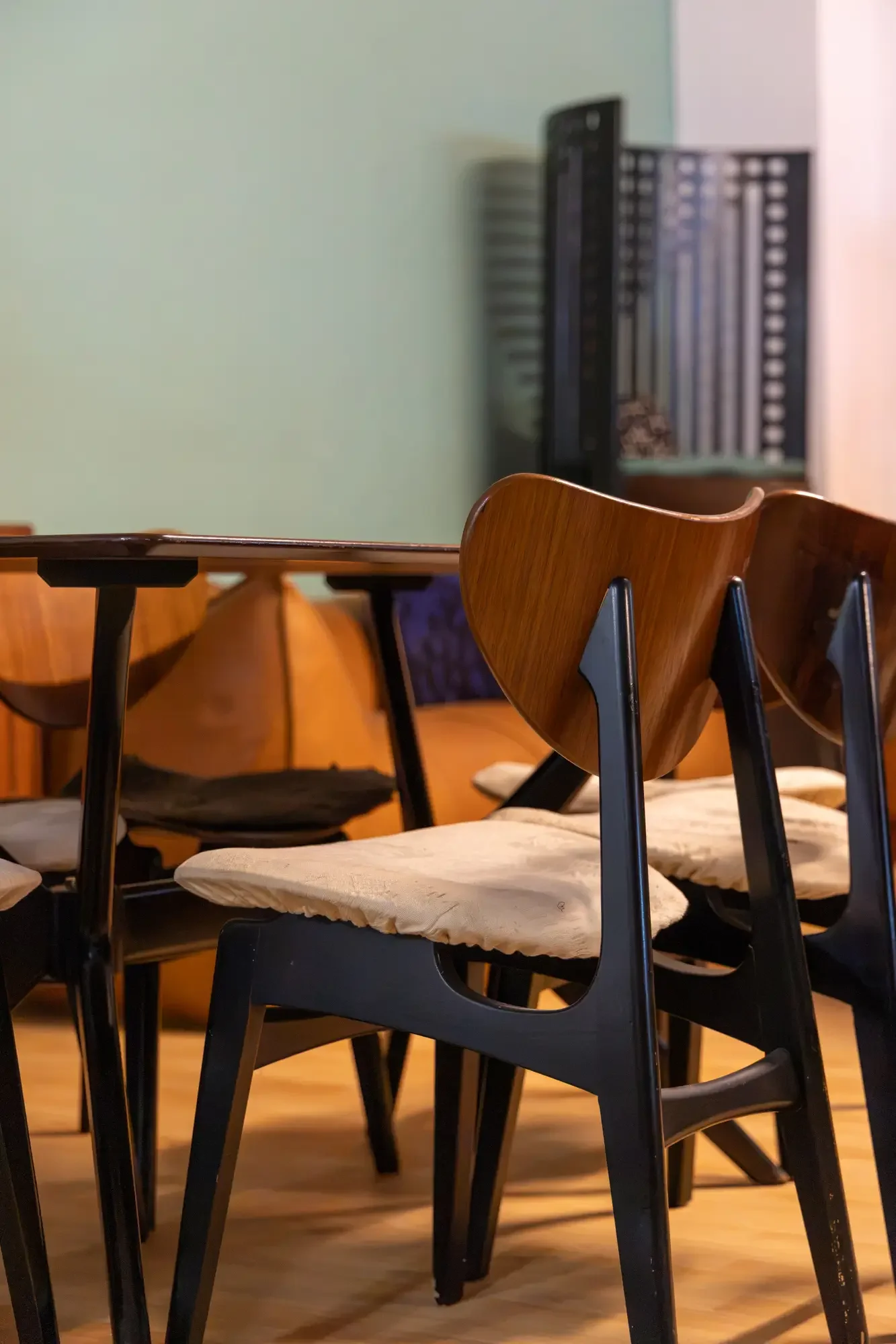 A room with multiple chairs and tables, with a green wall and a shelving unit in the background. Aymerick Rondeau Furniture Emporium Alhaurin second hand furniture shop