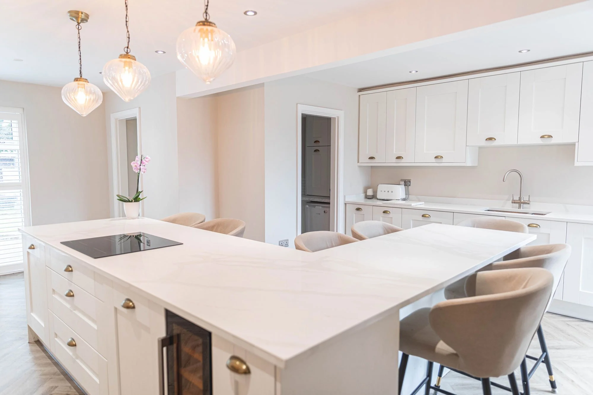 Modern kitchen with black cabinets, white marble countertop, and a vase with white flowers on the island.