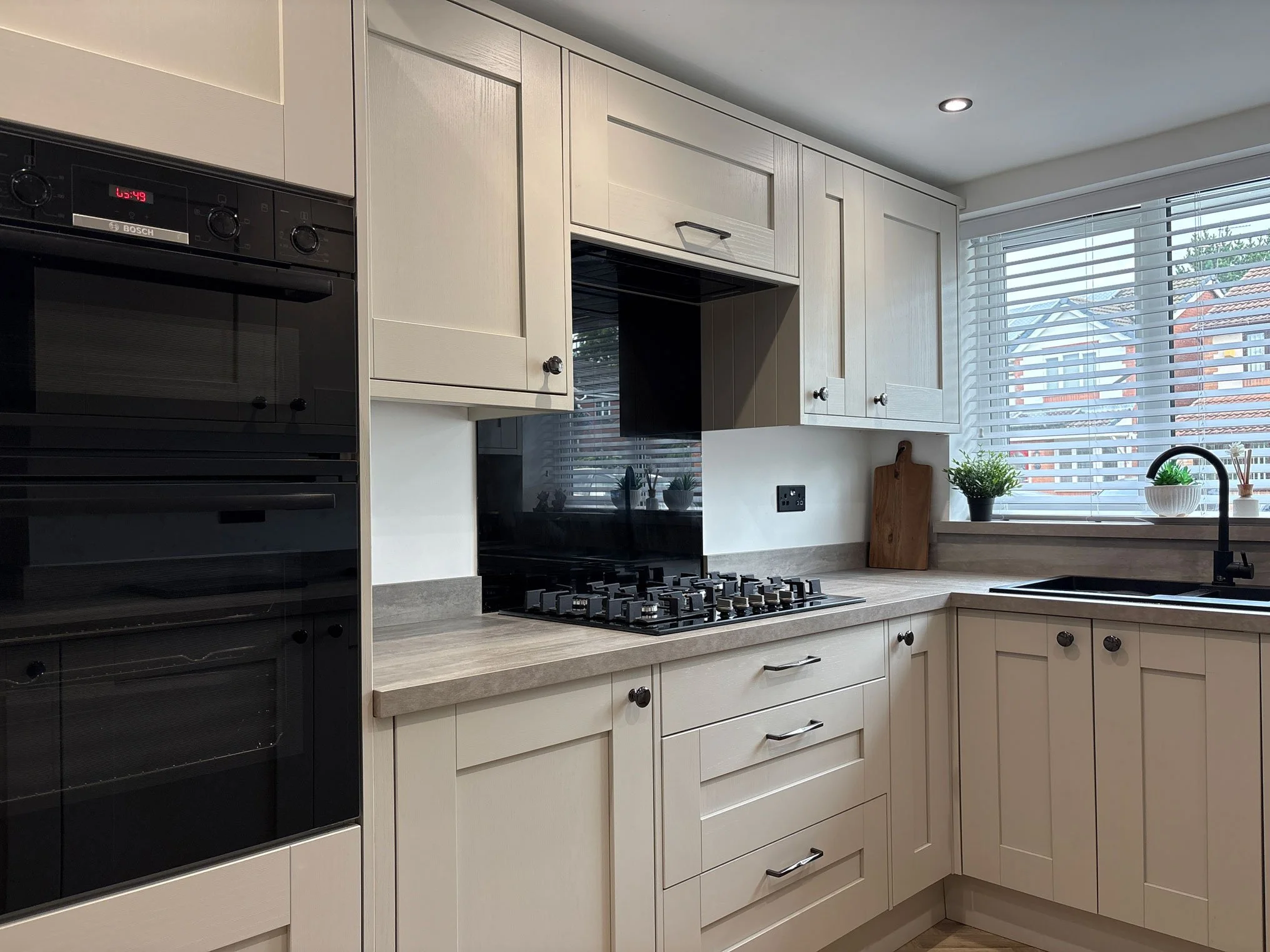 Modern kitchen with white cabinets, a kitchen island, pendant lights, and a large sliding glass door opening to outdoor greenery.