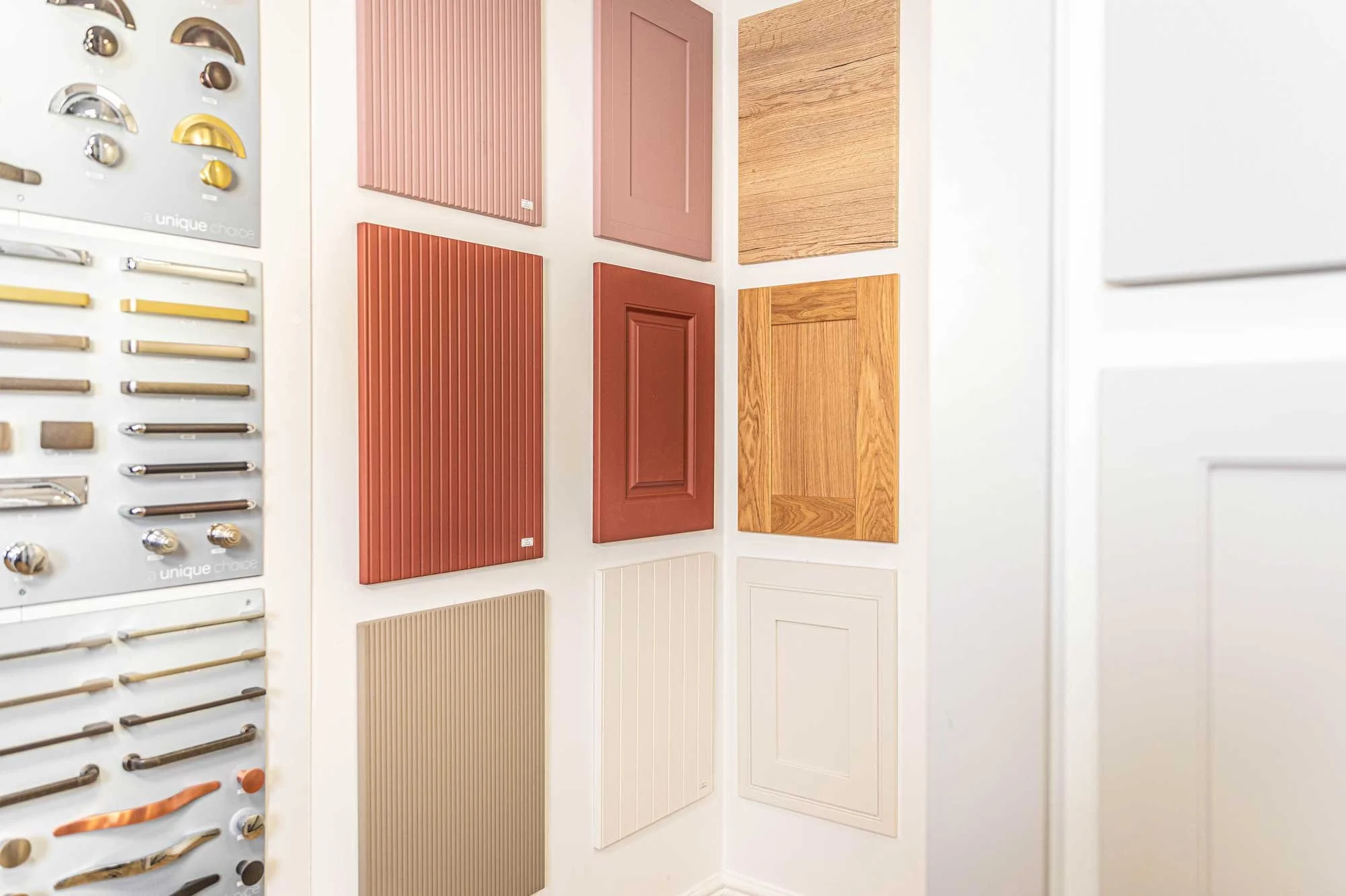 Display of various cabinet door styles and hardware samples on a wall at a showroom.