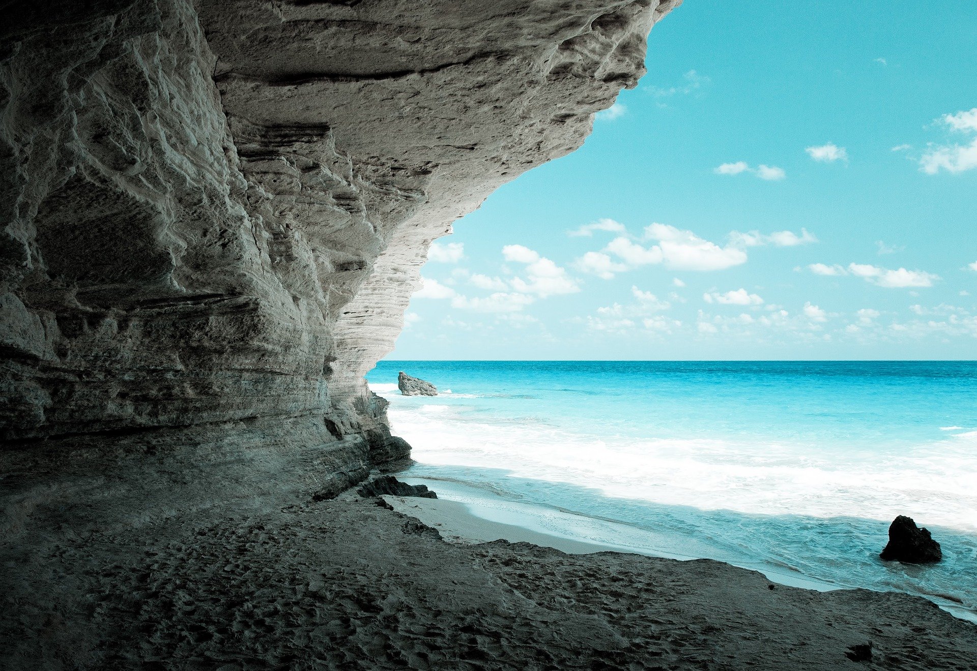 Scogliera sulla spiaggia con il mare e il cielo blu con nuvole
