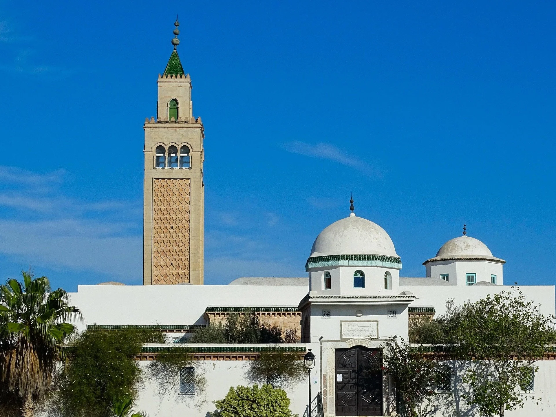 Torri e cupole di un edificio in stile marocchino, con un cielo azzurro sullo sfondo.