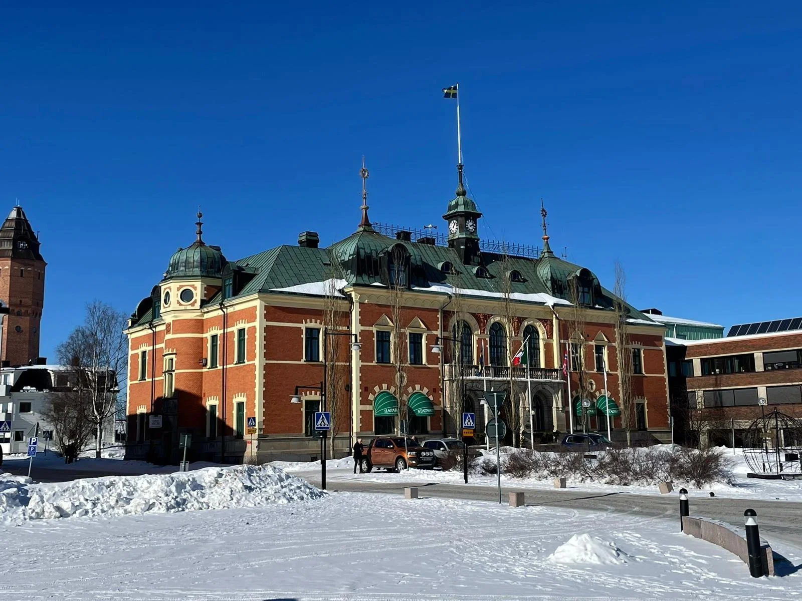 Edificio storico in stile classico con tetto verde, bandiera svedese e piazza innevata davanti