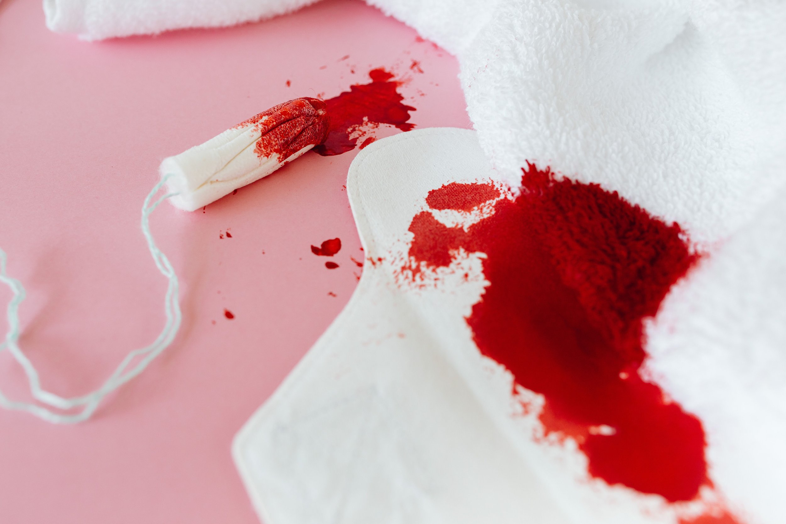 A white cloth with red powder spilled on it, bloodstains on a pink surface, and a rolled-up white cloth with blood on it.