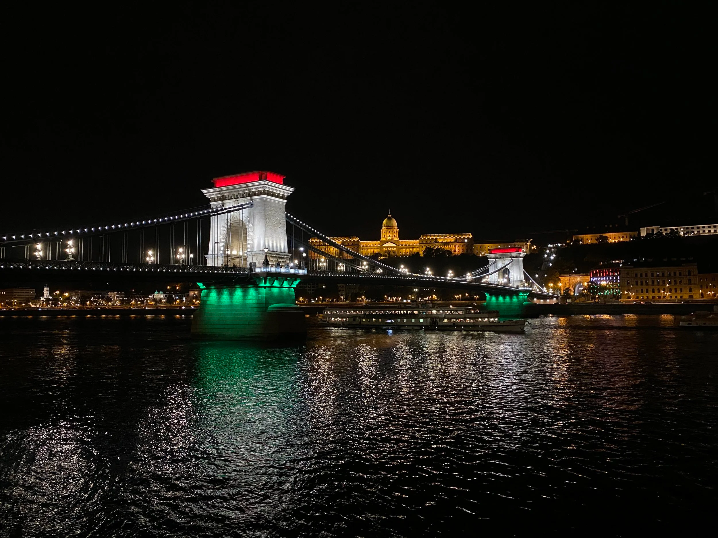 Chain Bridge lit up in Hungarian National colors with Royal Palace in the background in Budapest, Hungary