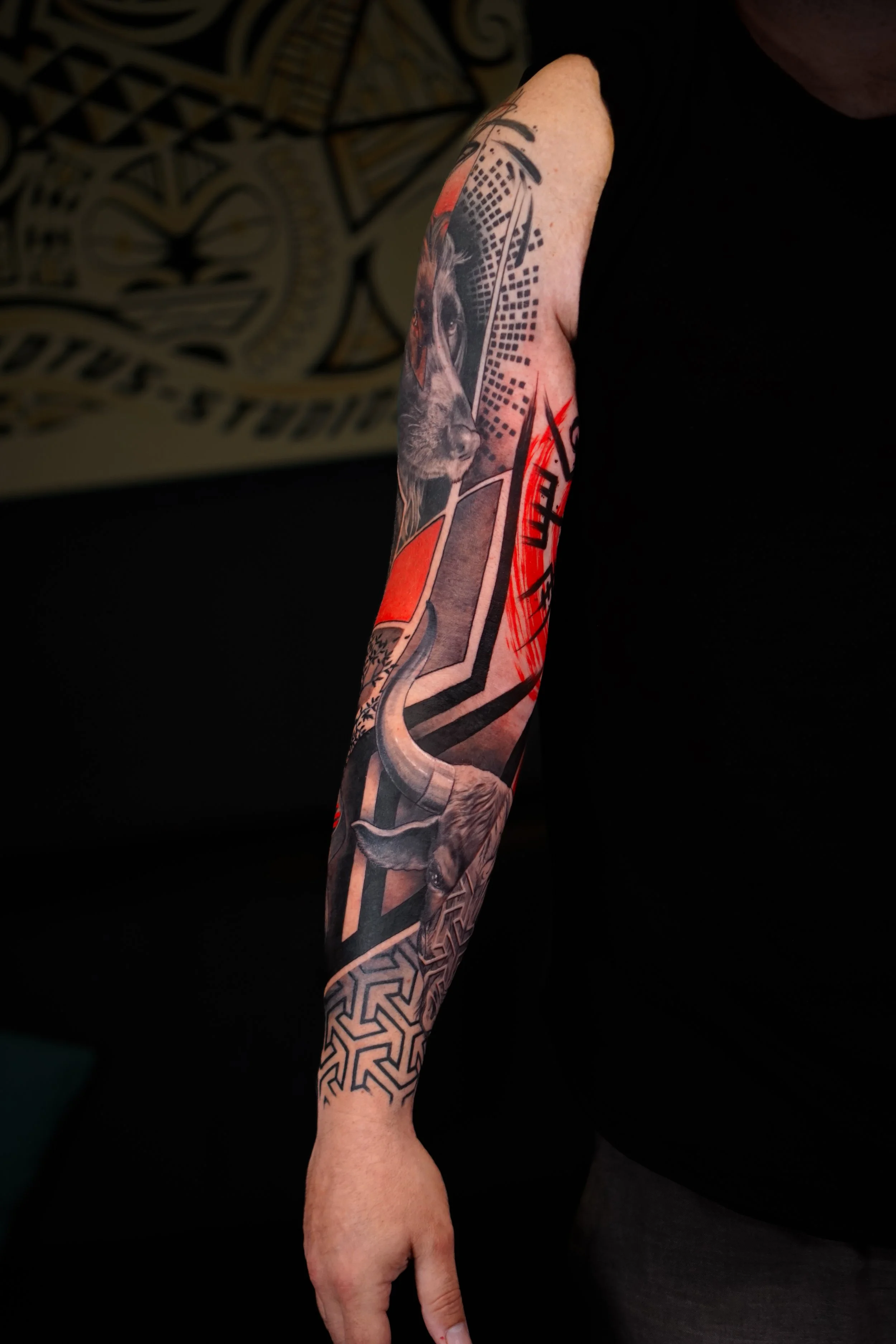 A person's arm with a colorful tattoo featuring a wolf's face, geometric patterns, and red accents.