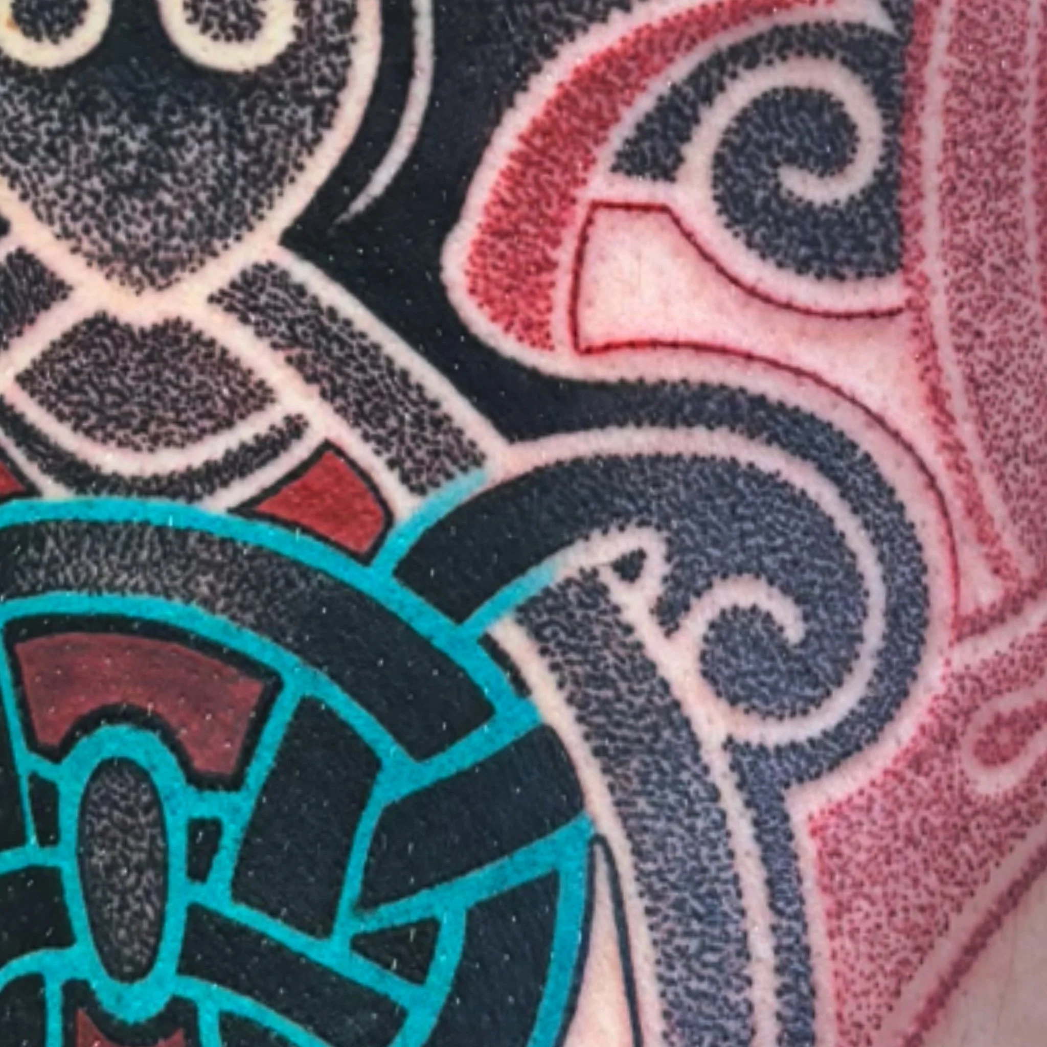 Close-up of a detailed, colorful pattern on a textured surface, featuring swirls and geometric shapes in black, pink, blue, and teal colors.