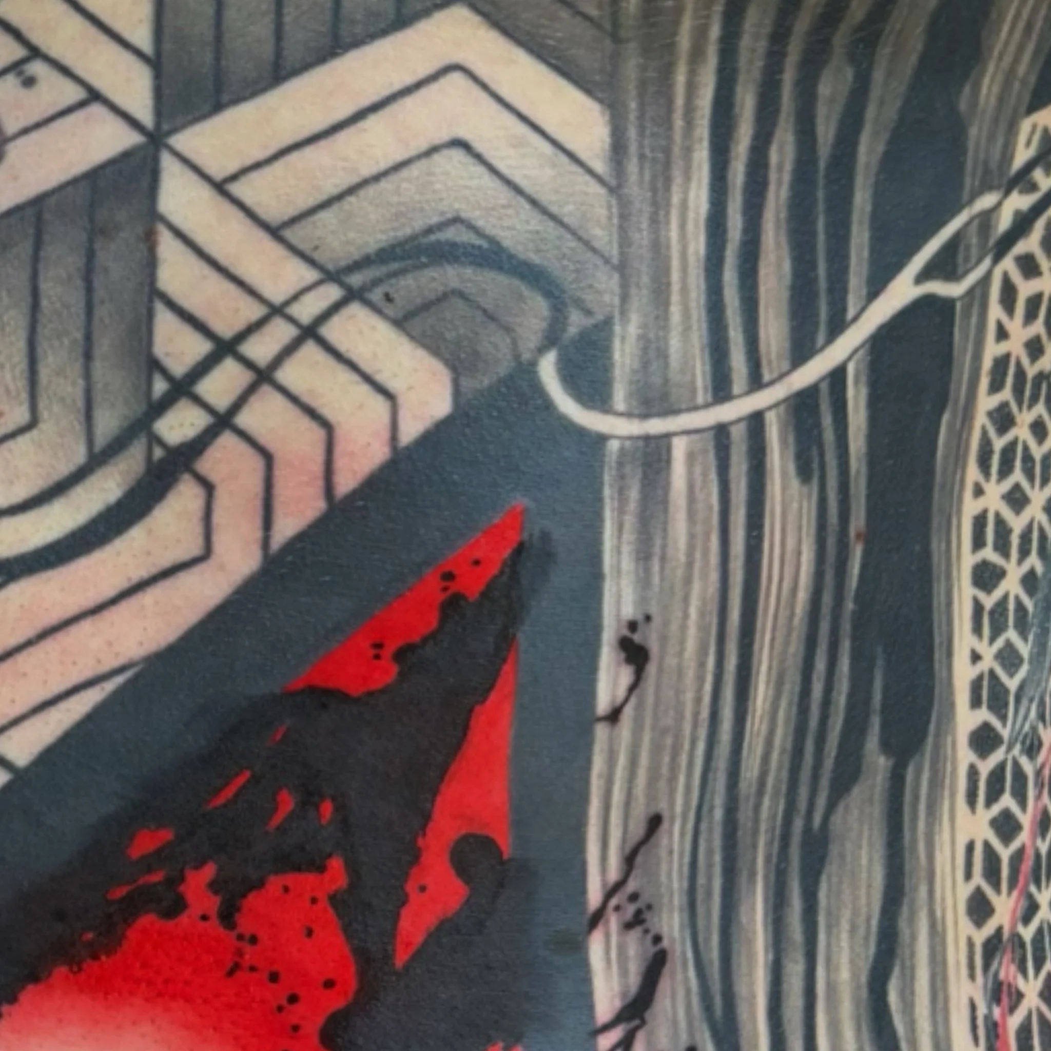 Close-up of intricate black, white, and red geometric design on a surface, possibly fabric or art piece.