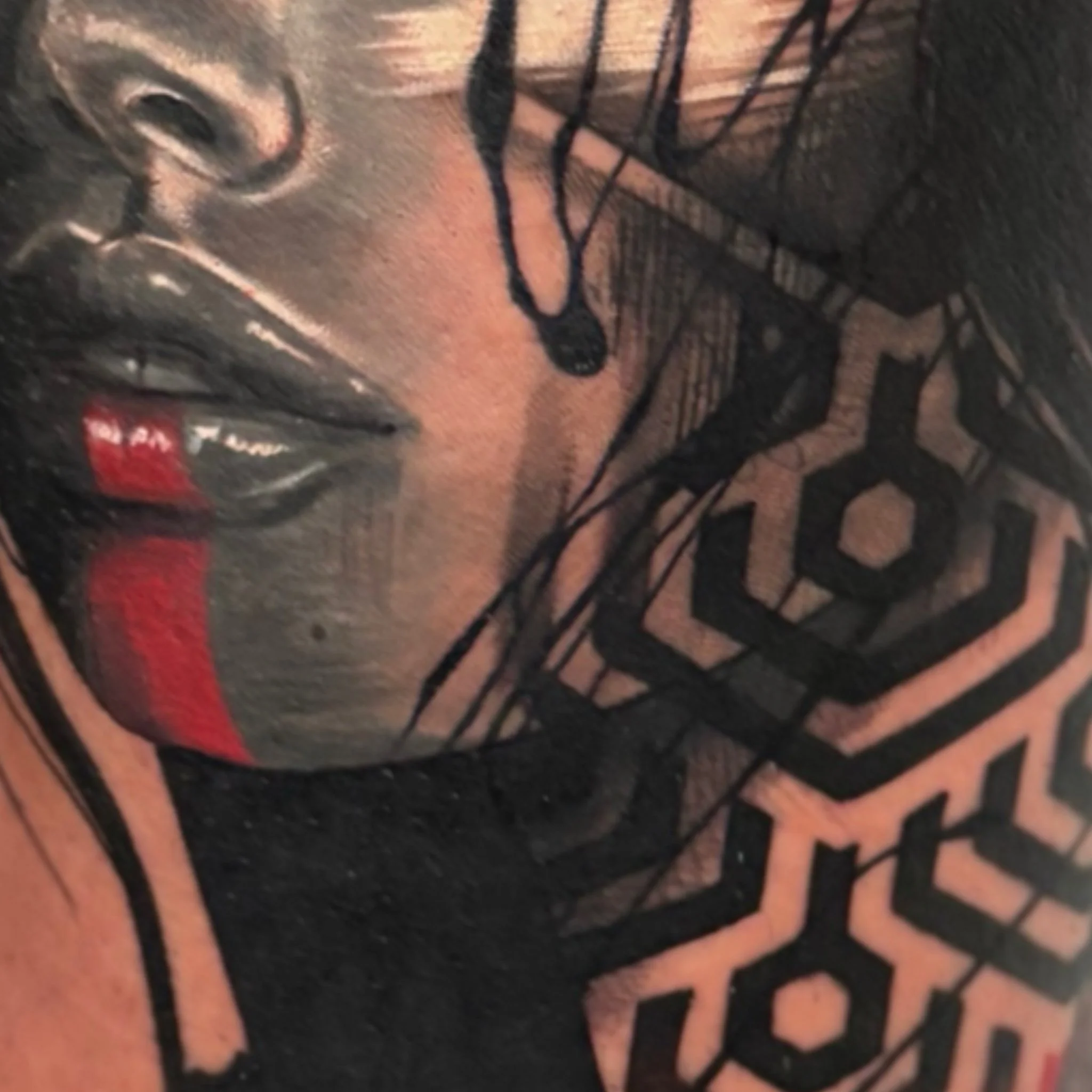 Close-up of a tattoo on a person's skin featuring a black and pink design with detailed line work.