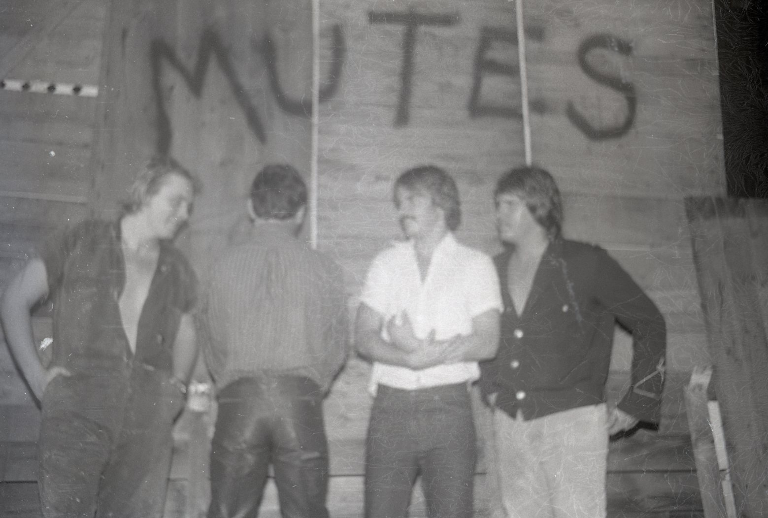 Four women standing in a gymnasium with a banner overhead that says 'WREST' with the rest obscured.