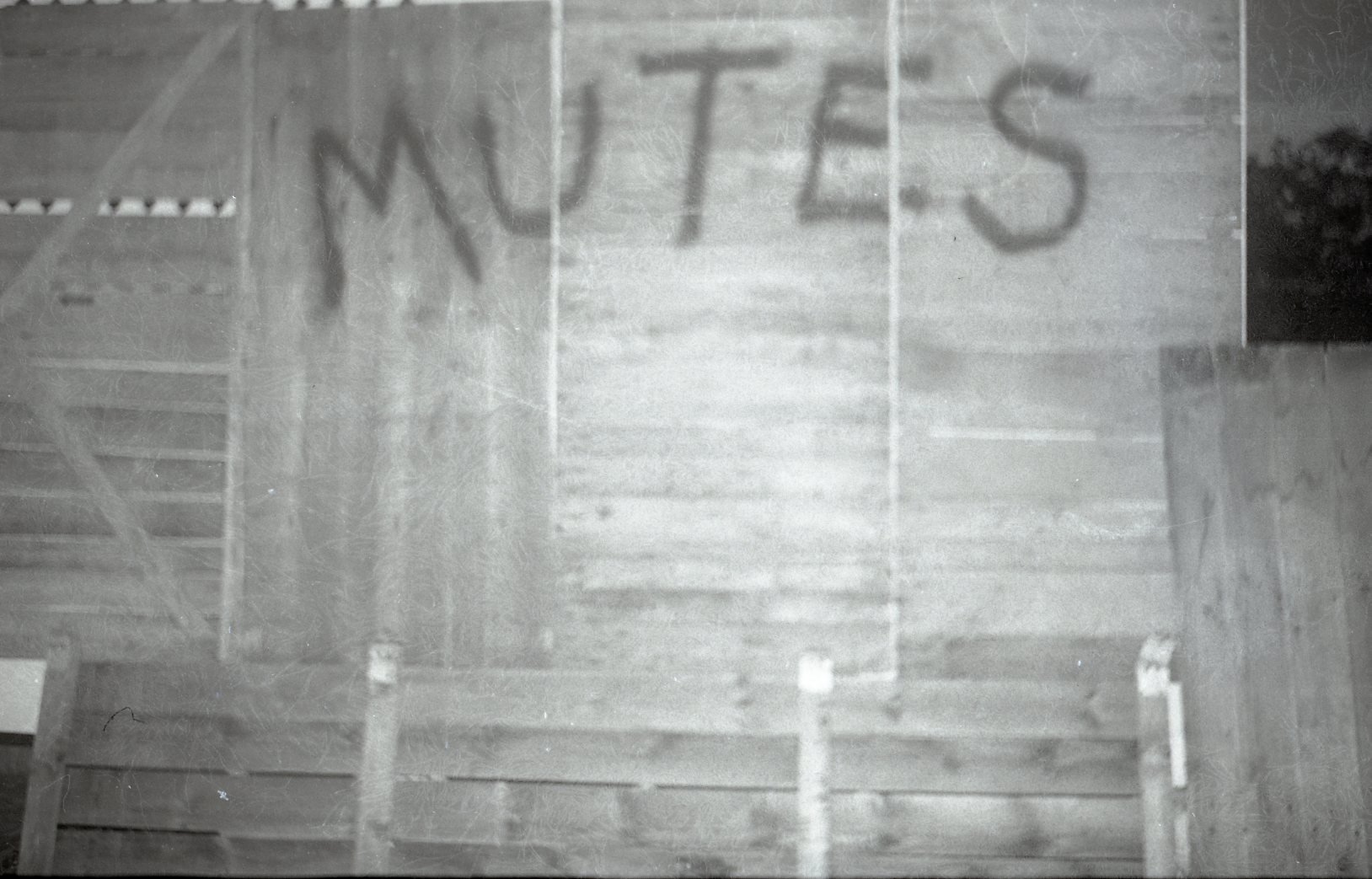 A black and white image of a basketball court viewed from above, with a shadow of the word 'WUTIES' projected onto the court's surface.