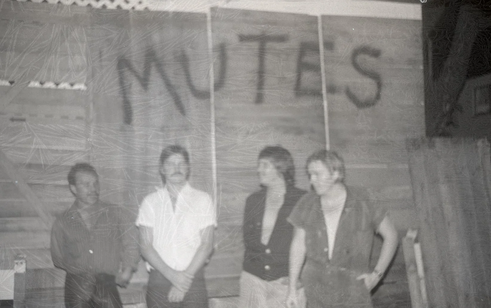 Four women standing in front of a staircase with a sign above that reads 'WOMEN'.