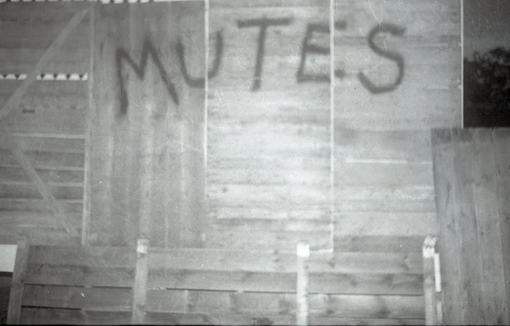 Shadow of the word 'MUTES' cast on a wooden staircase.