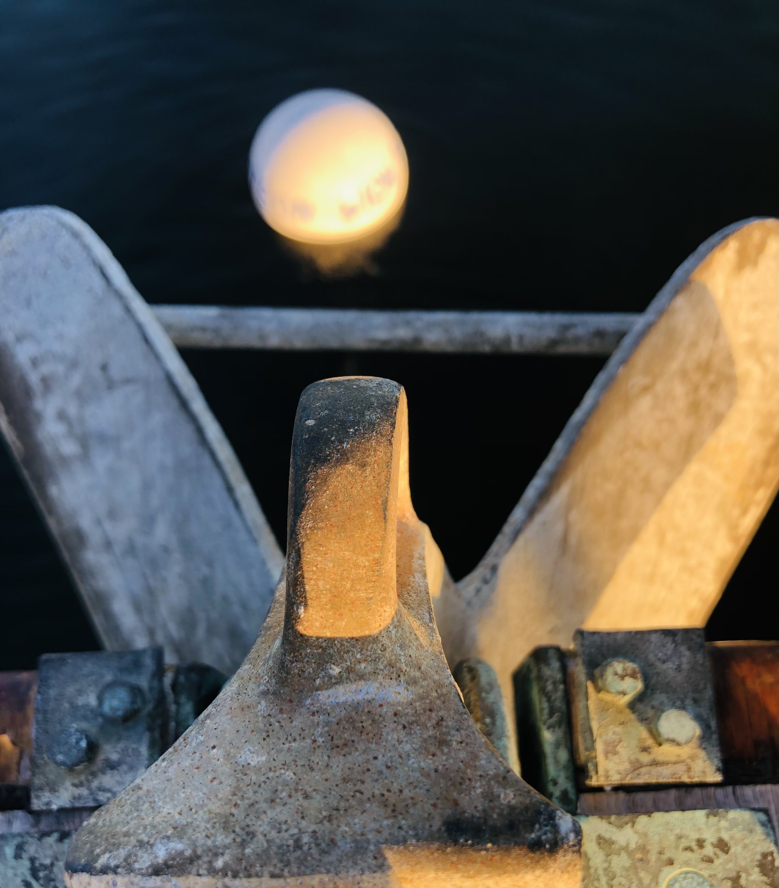 A close-up of a lighthouse model made of rocks and pebbles, with the moon visible in the background.