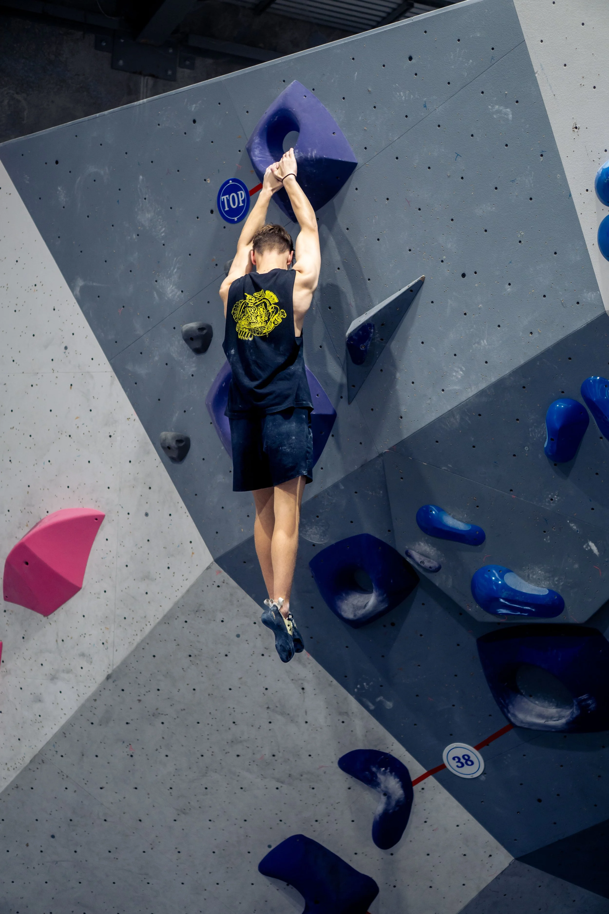 A person rock climbing on an indoor climbing wall using colorful holds, with a 