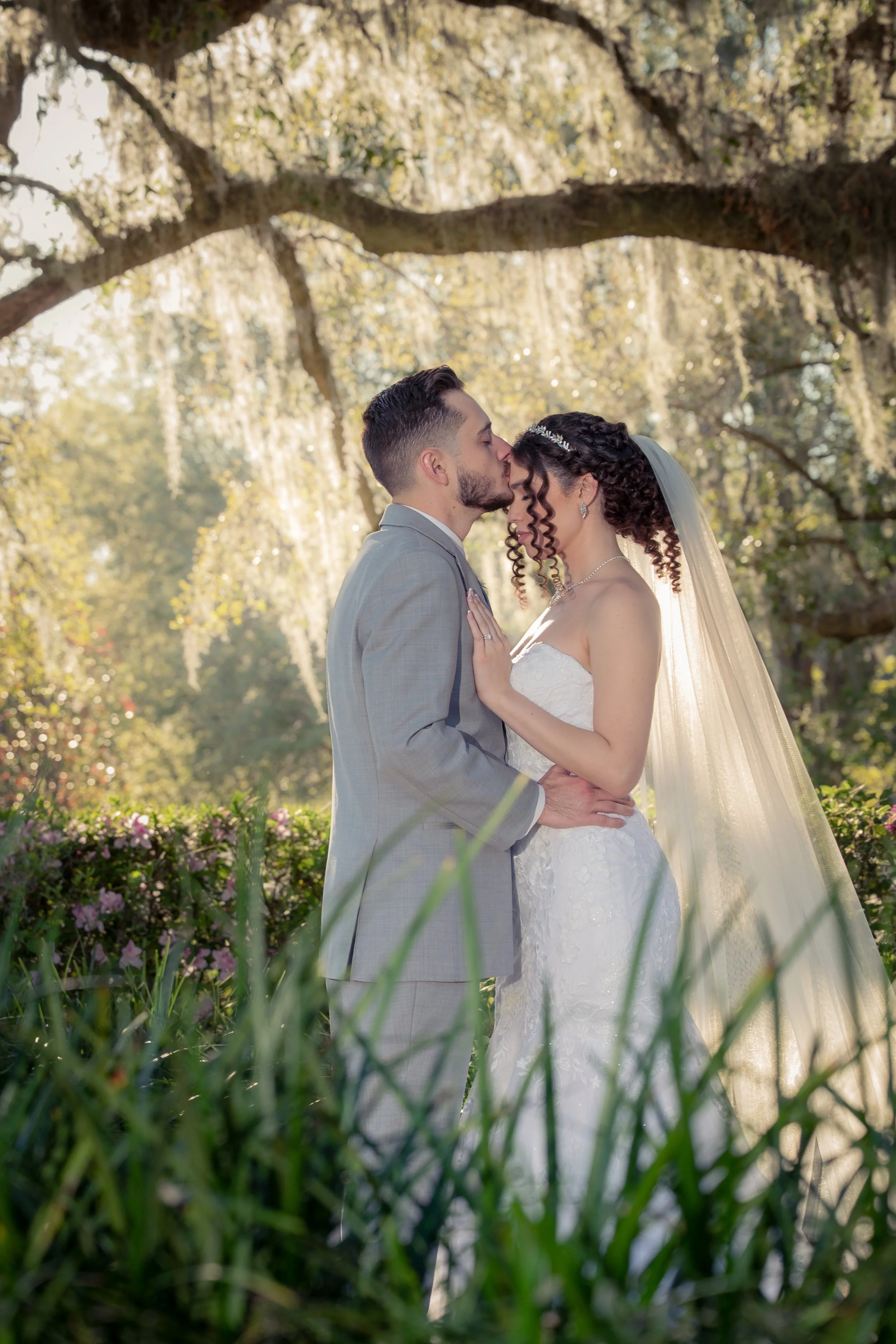 Bride and groom sharing a quiet moment beneath a moss-covered oak tree during an intimate Florida wedding surrounded by natural beauty.
