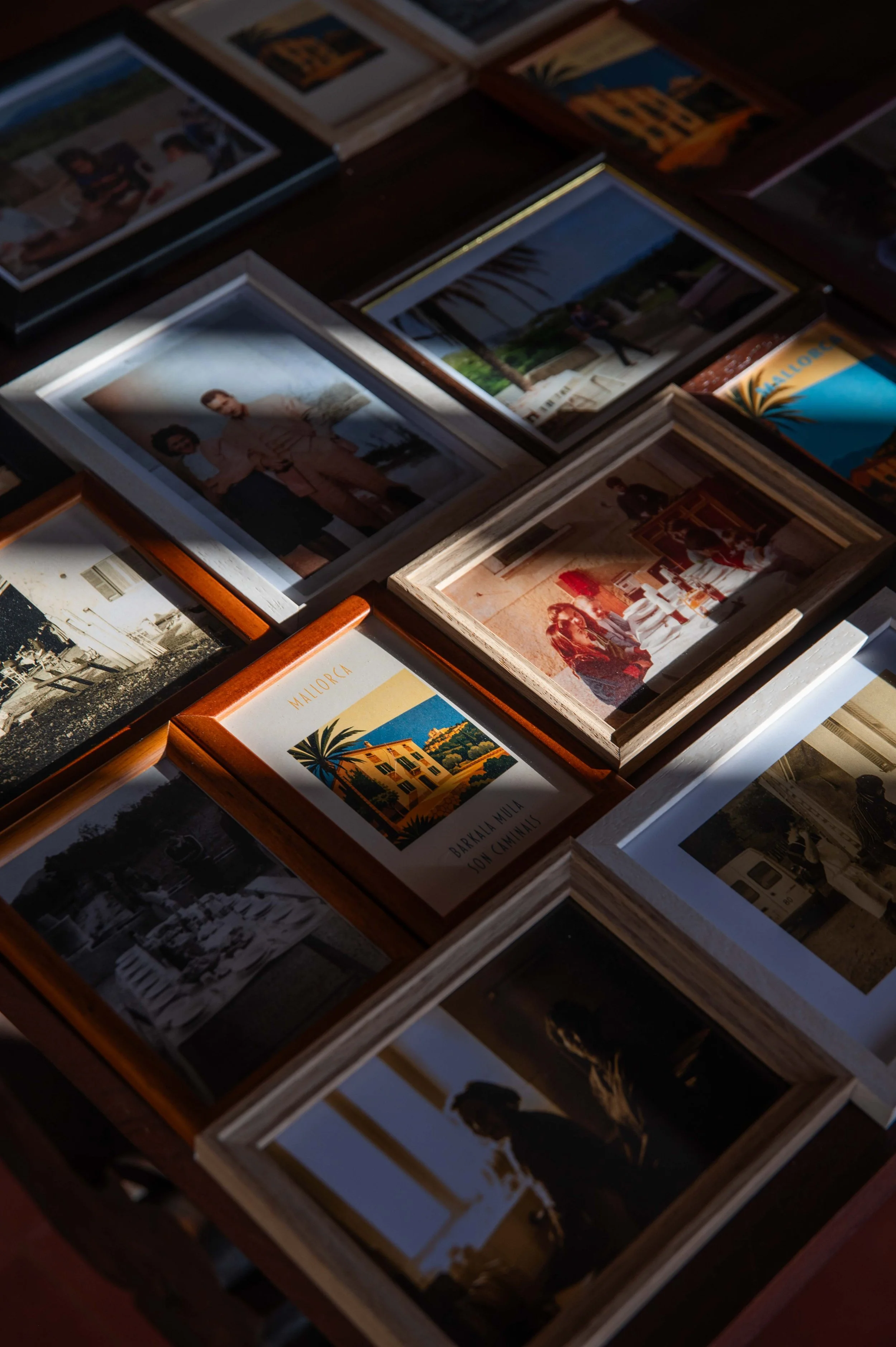 A collection of framed photographs and postcards arranged on a surface, some in wooden frames and others in card holders, capturing various scenes and people.