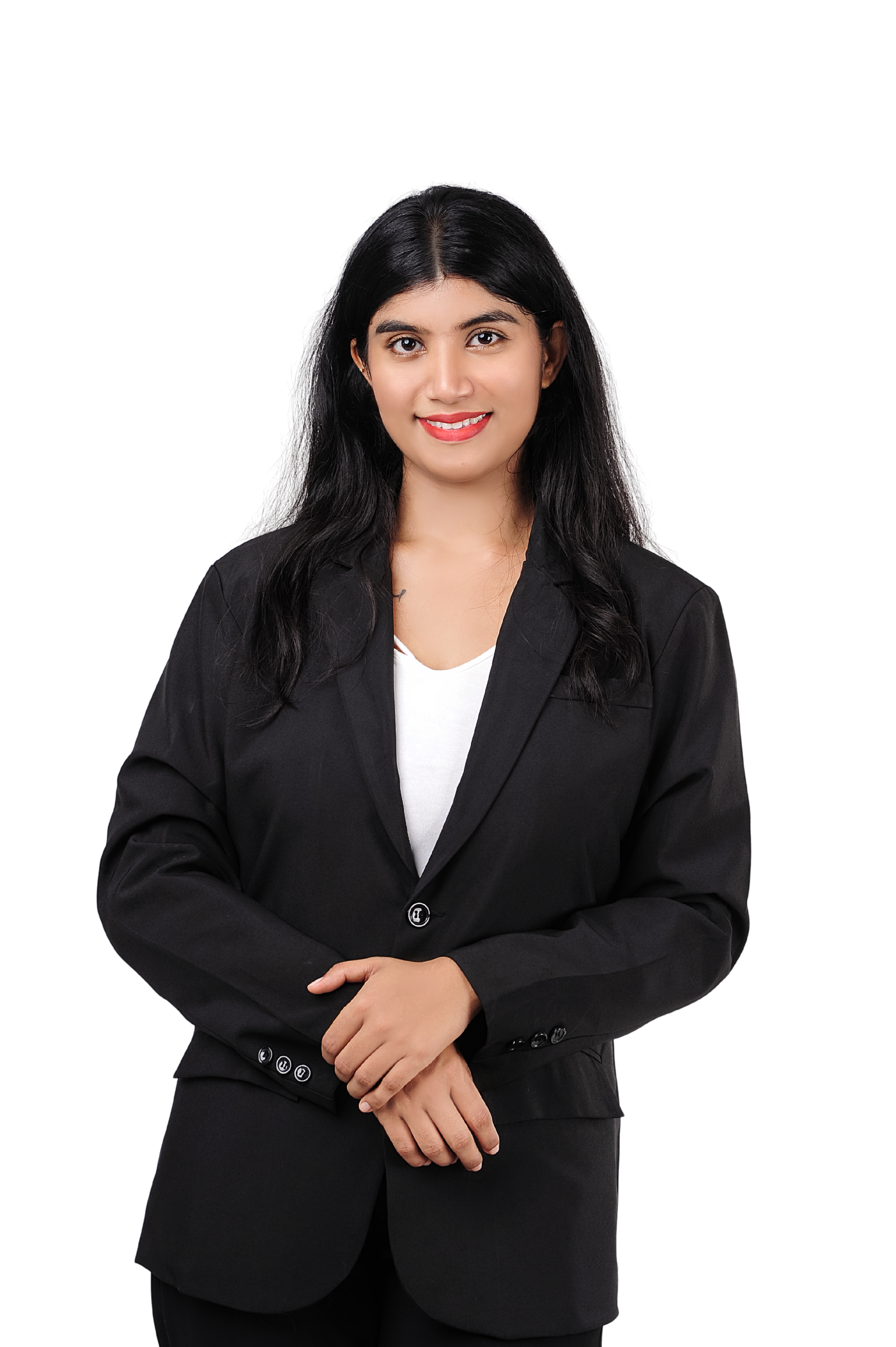 A woman dressed in a black blazer and white top, smiling with her hands clasped in front of her, standing against a black background.