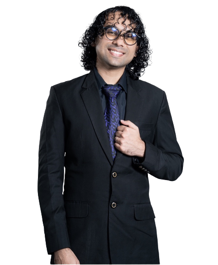 A man with curly black hair, glasses, and a big smile wearing a black suit, blue tie, and black shirt posing against a dark background.