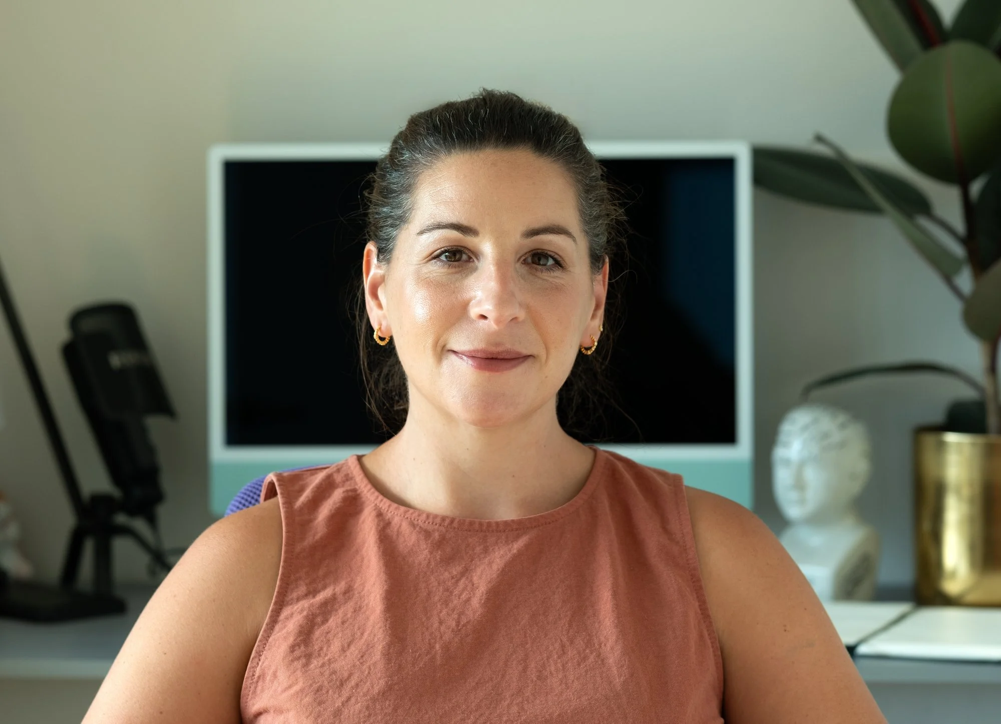 Natalie May sits at her desk and smiles to the camera