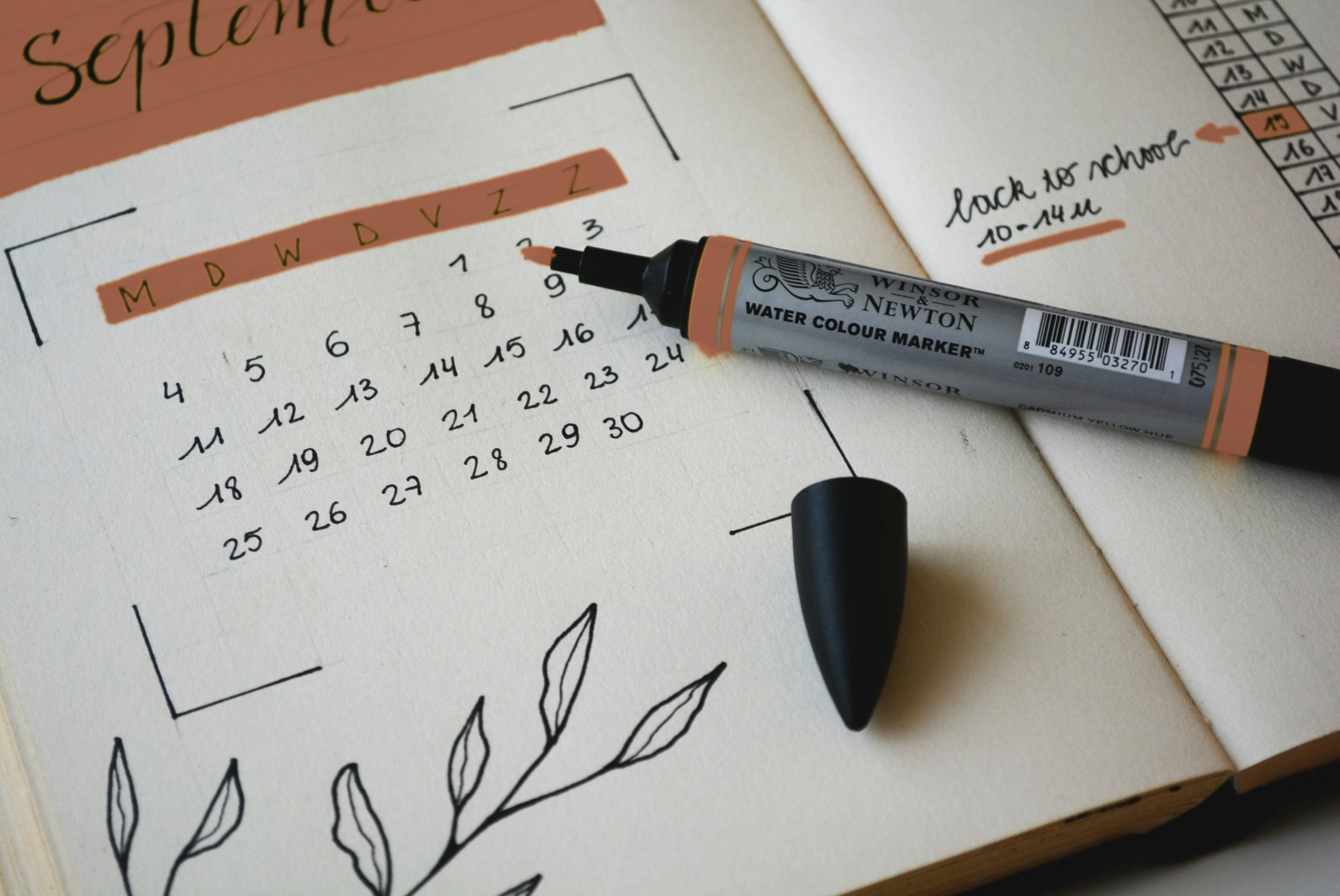 A journal page with a weekly schedule and a pen resting on the page.