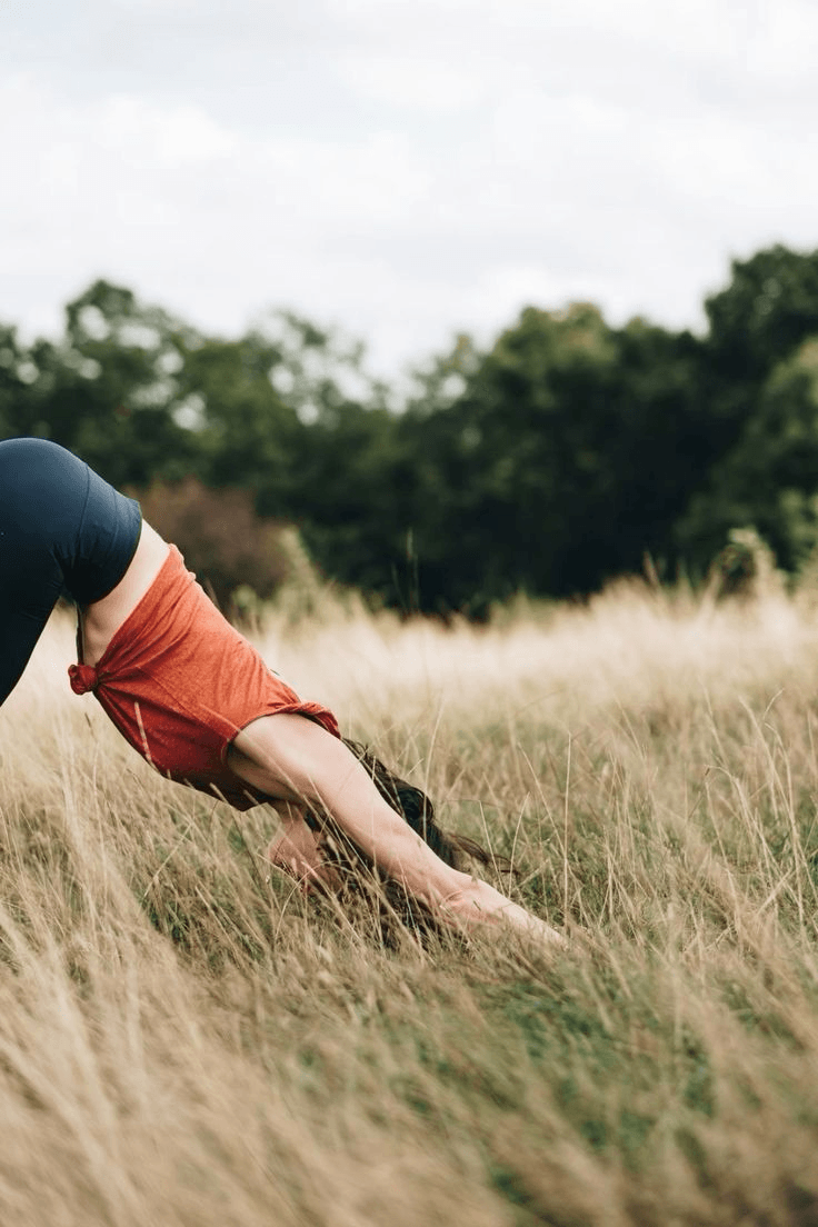 Person practicing yoga in a sunlit meadow of tall grass