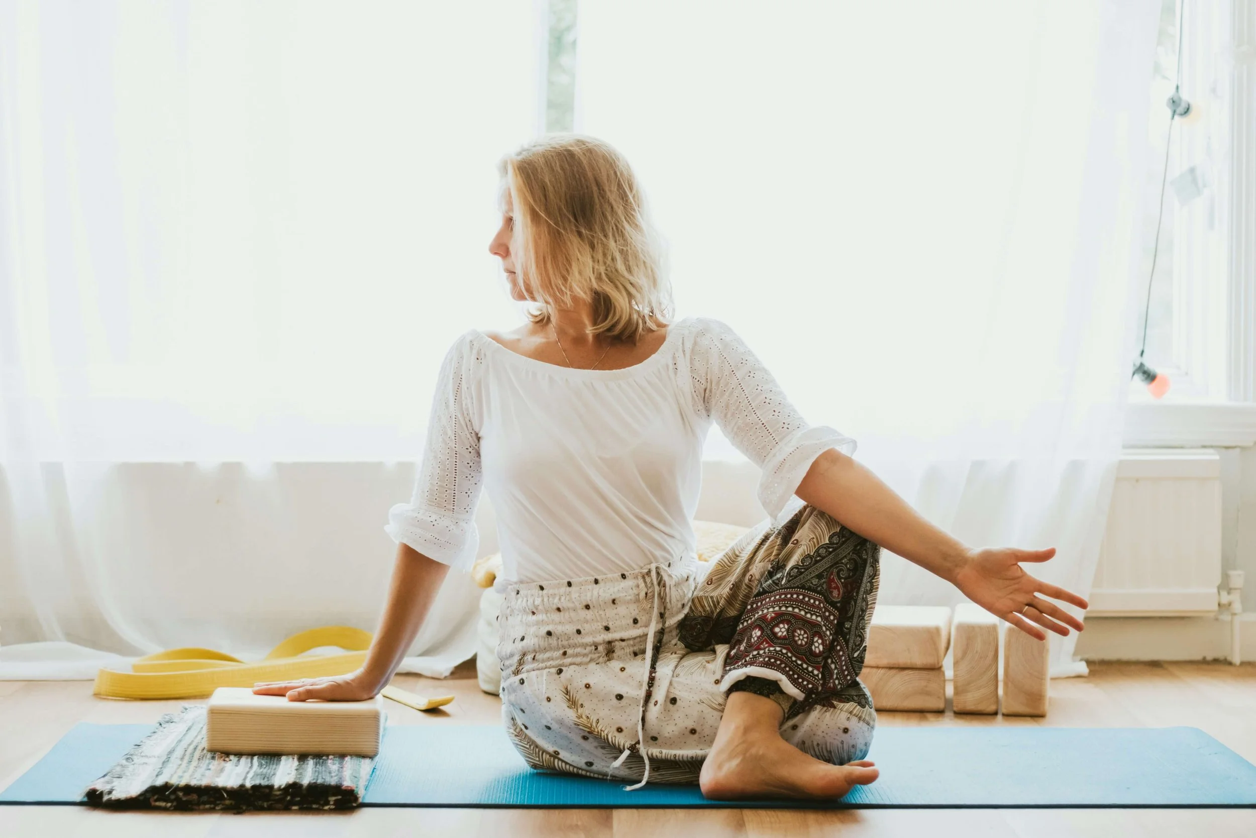Woman practicing seated yoga pose on a blue mat in a bright room