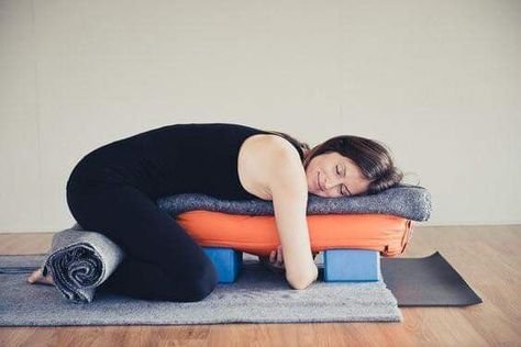 Woman relaxing in a side-lying yoga pose on a bolster and mat
