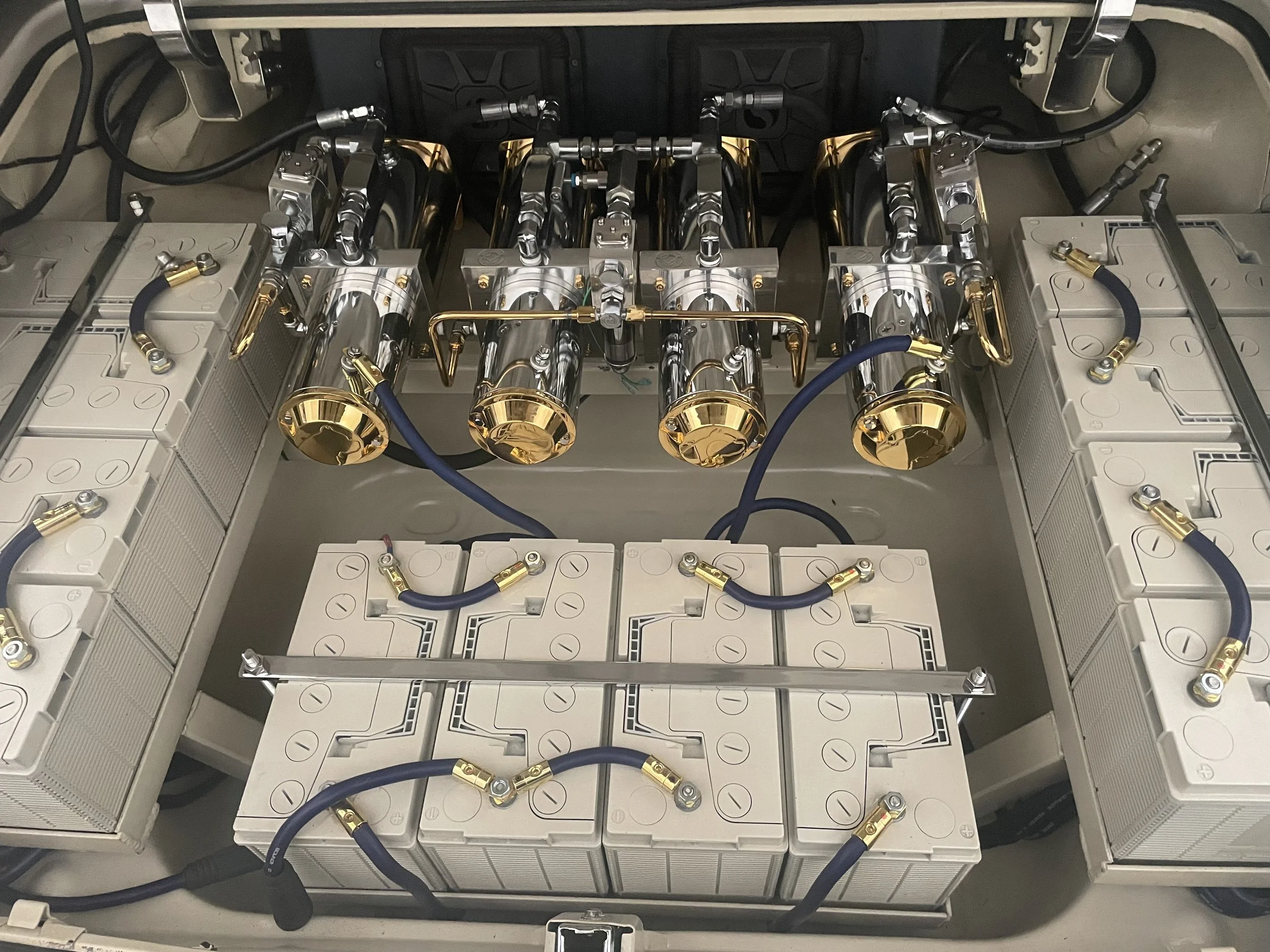 A close-up view of an open electrical cabinet containing arranged circuit breakers, metal tubes, and electrical wiring, with emphasis on metallic and gold-colored components.
