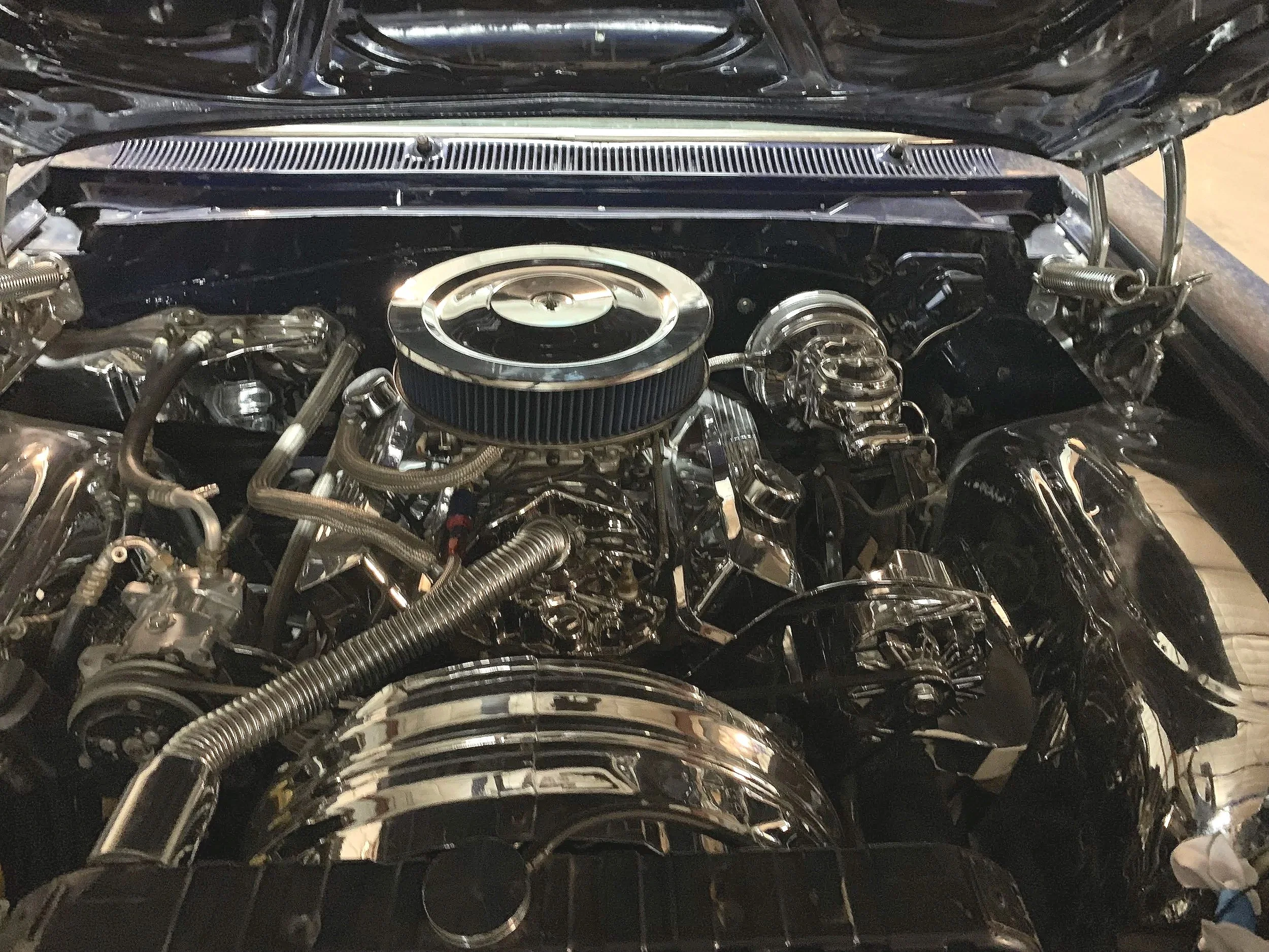Close-up of a polished car engine with chrome parts and metal hoses.