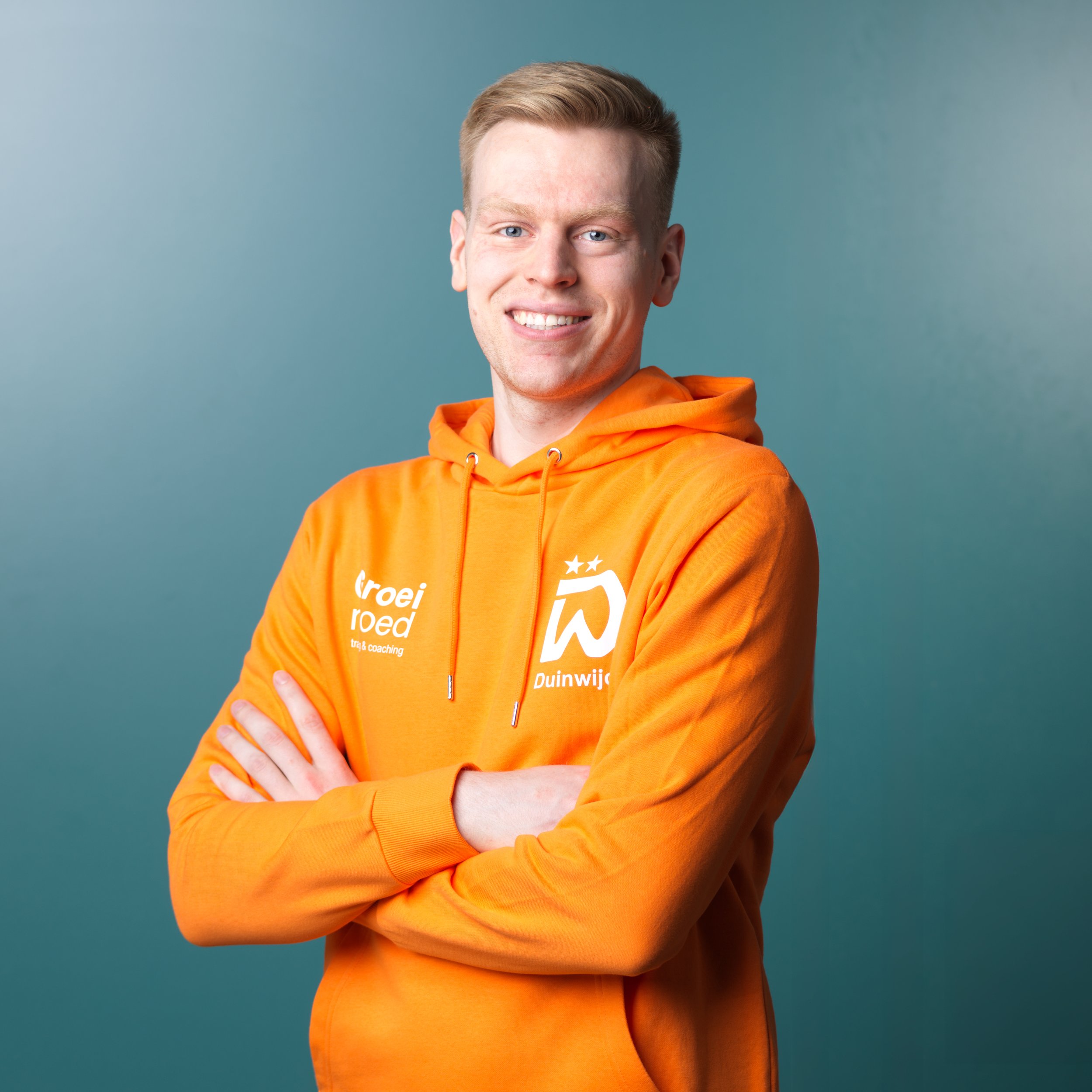 Man speelt badminton op een sporthal met digitale scoreborden op de achtergrond.