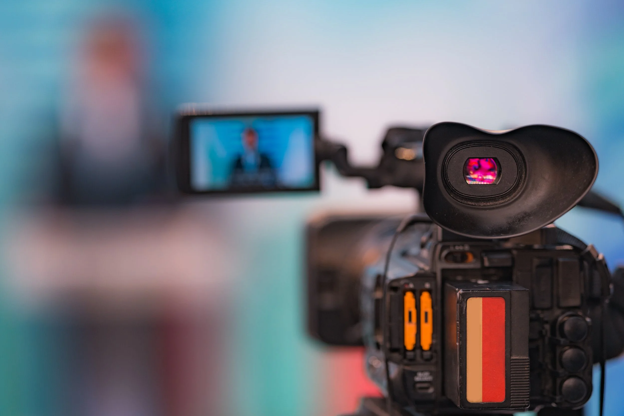 Close-up van een professionele videocamera met het scherm toont een man die een presentatie geeft.