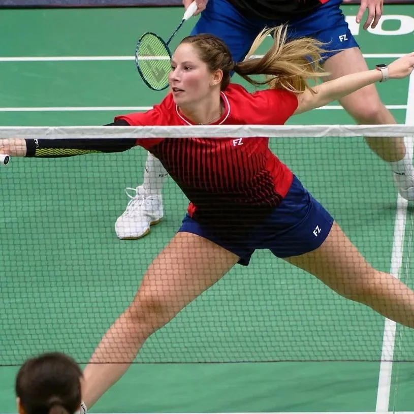 Silhouet van een persoon met hand op de kin, mogelijk in een sportomgeving met doelen of netten op de achtergrond.