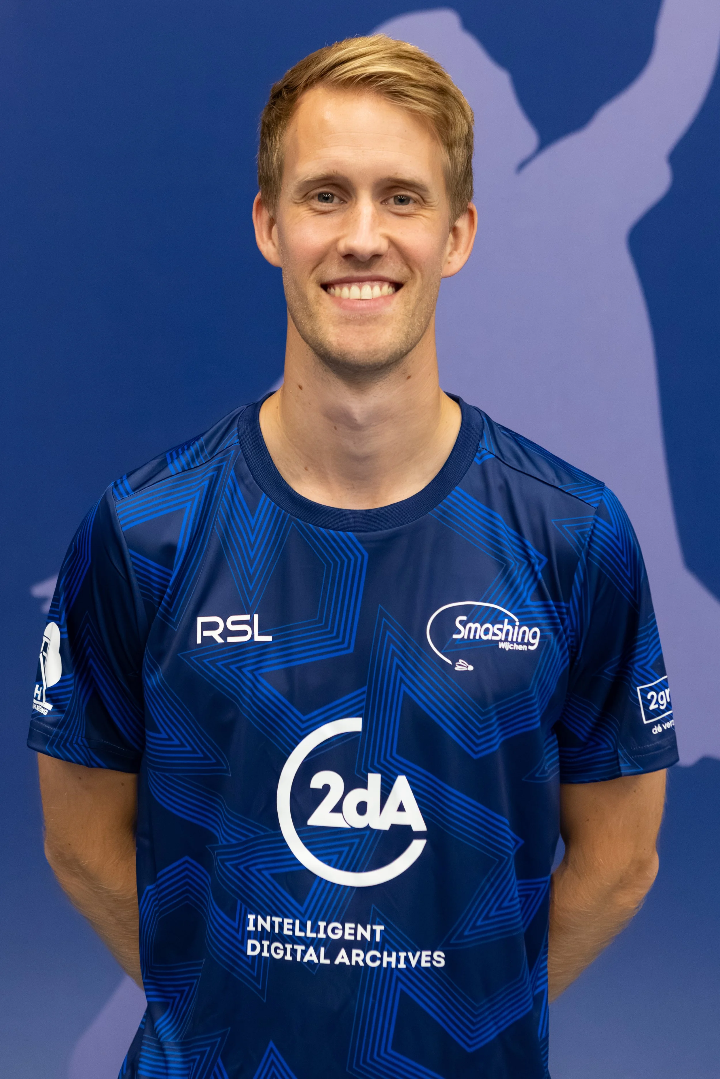 Badmintonner Marijn Put, in zijn BC Smashing clubshirt voor een fabric achterwand