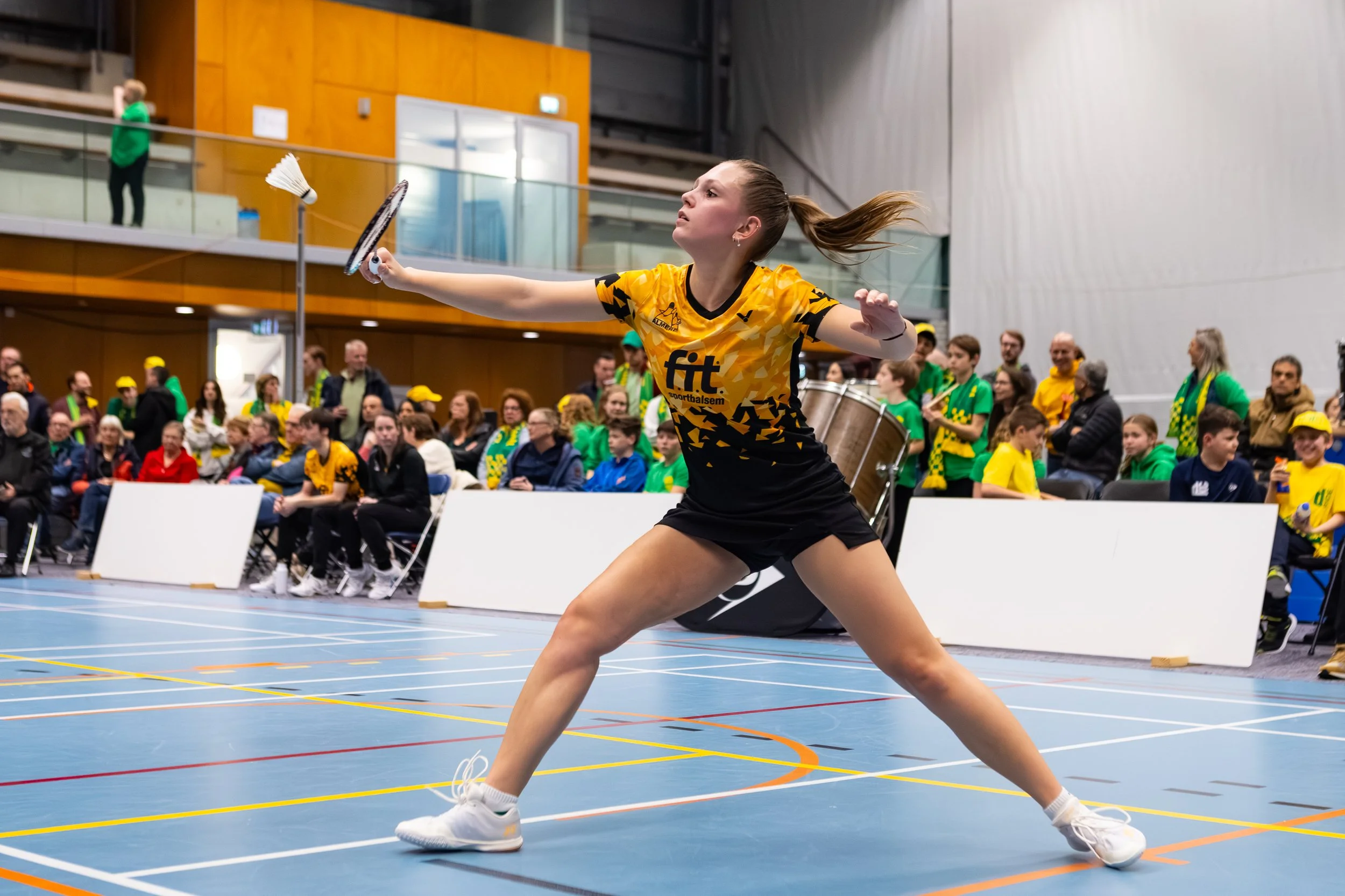 Diede Odijk speelt badminton in een sporthal, omringd door een publiek dat toekijkt.
