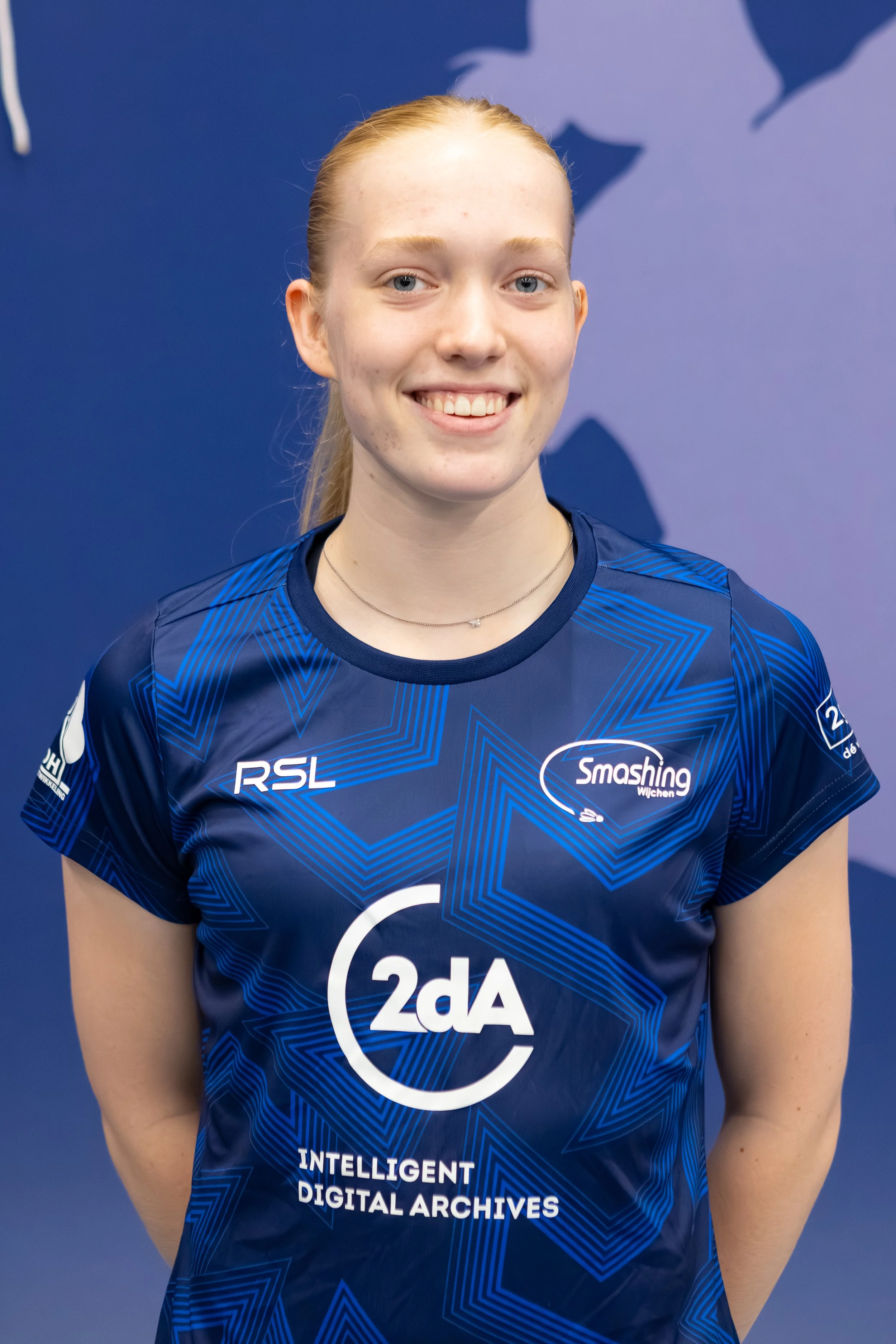 Badmintonner Inger Pothuizen in haar BC Smashing clubshirt voor een fabric achterwand