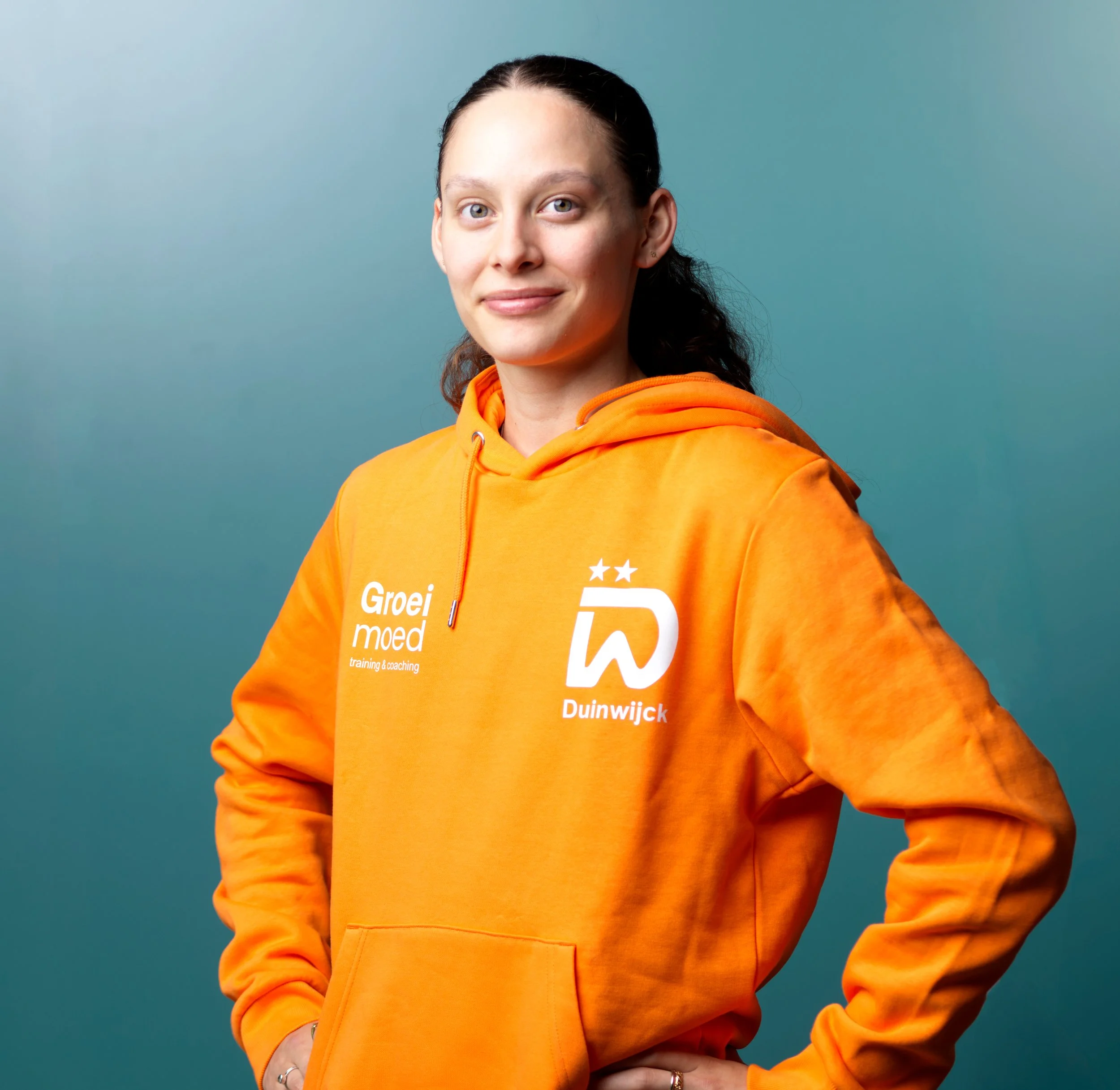 Een vrouwelijke badmintonspeelster in een blauw en gele sportoutfit, die een overwinning viert met een vuist in de lucht in een sporthal.