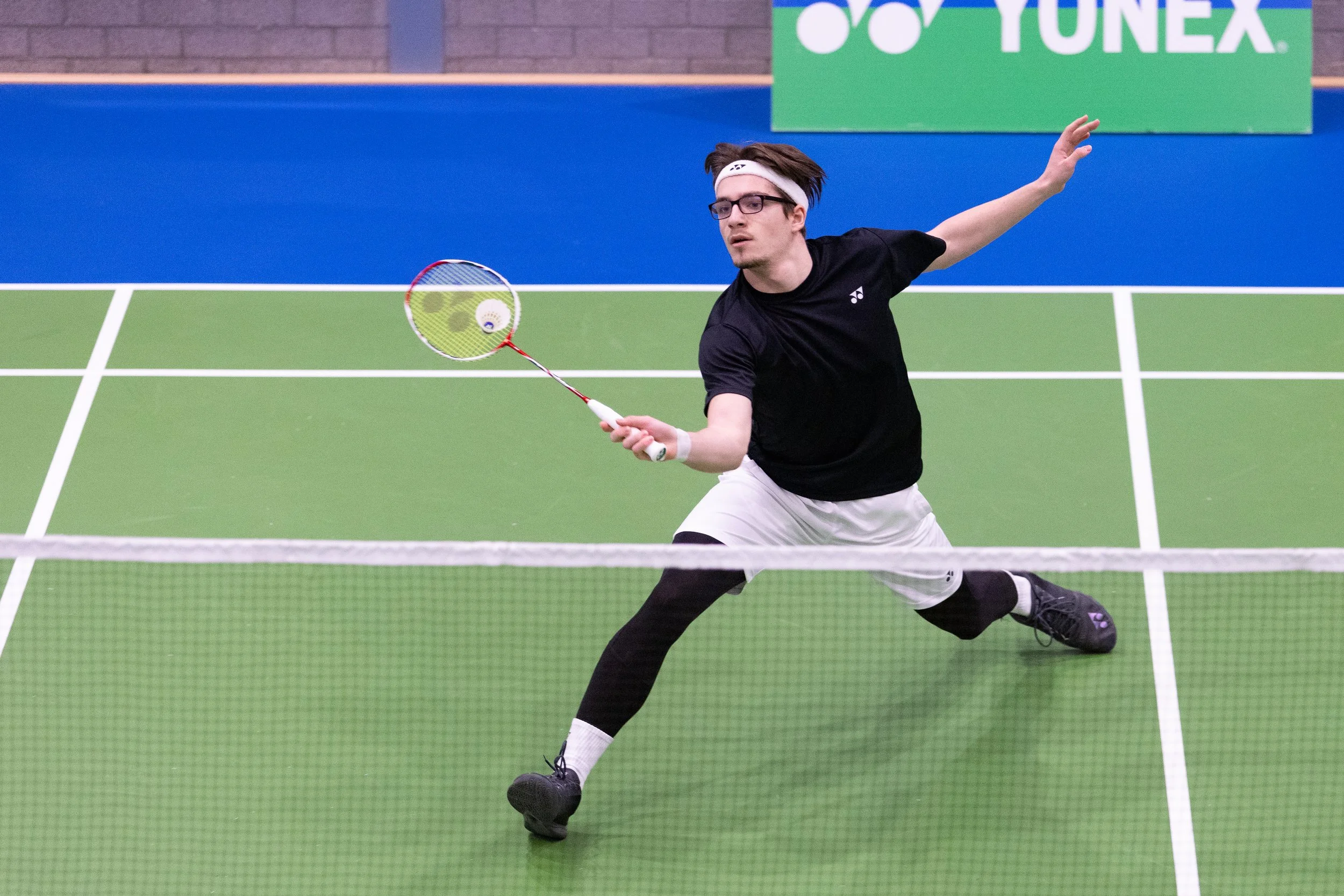 Luca Wiechmann die een shuttle slaat tijdens een badmintonwedstrijd in de sporthal van BC Duinwijck