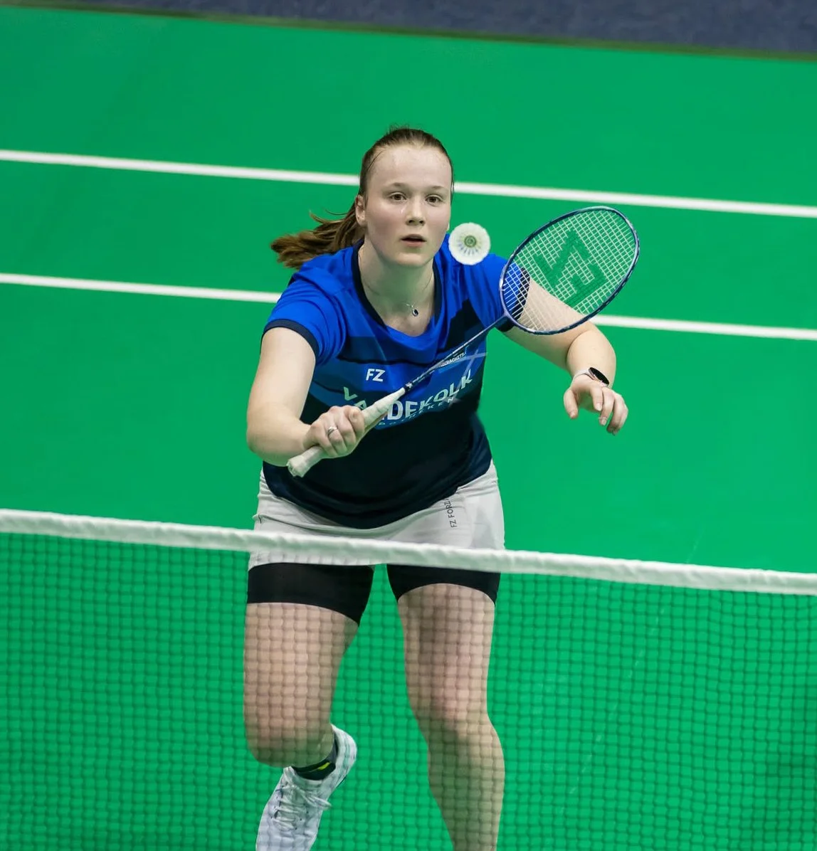 Kelly van Buiten speelt badminton op groene indoor baan.