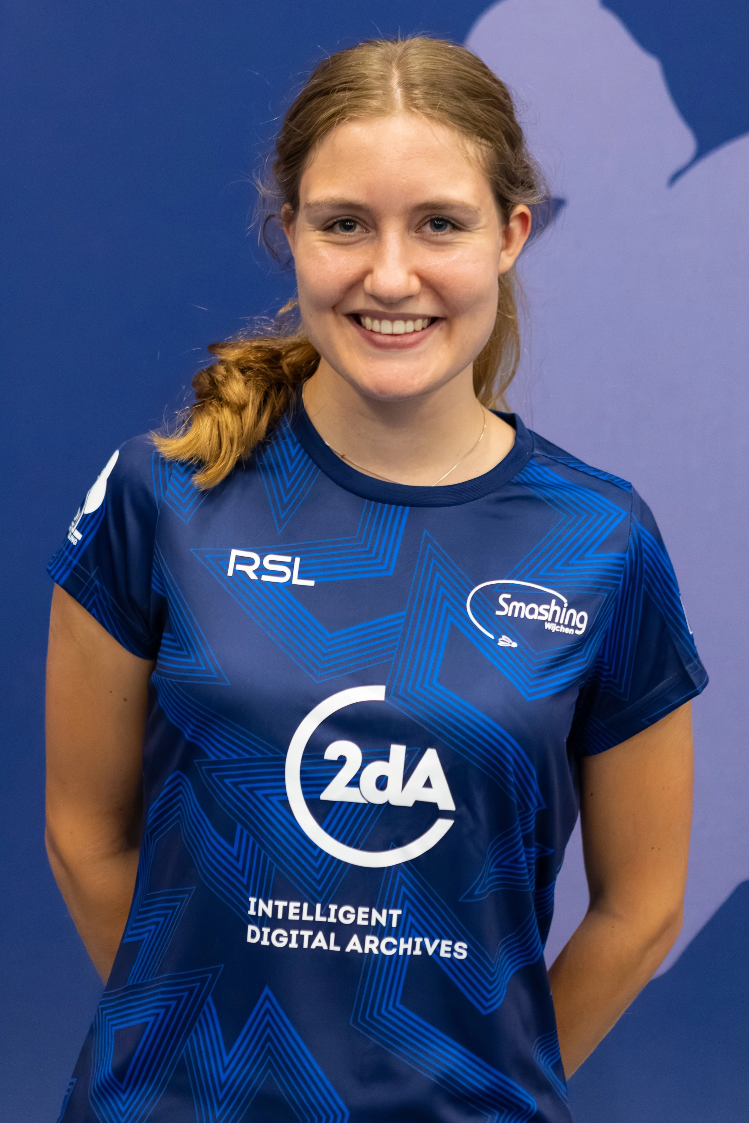 Badmintonner Leonie Rovers in haar BC Smashing clubshirt voor een fabric achterwand