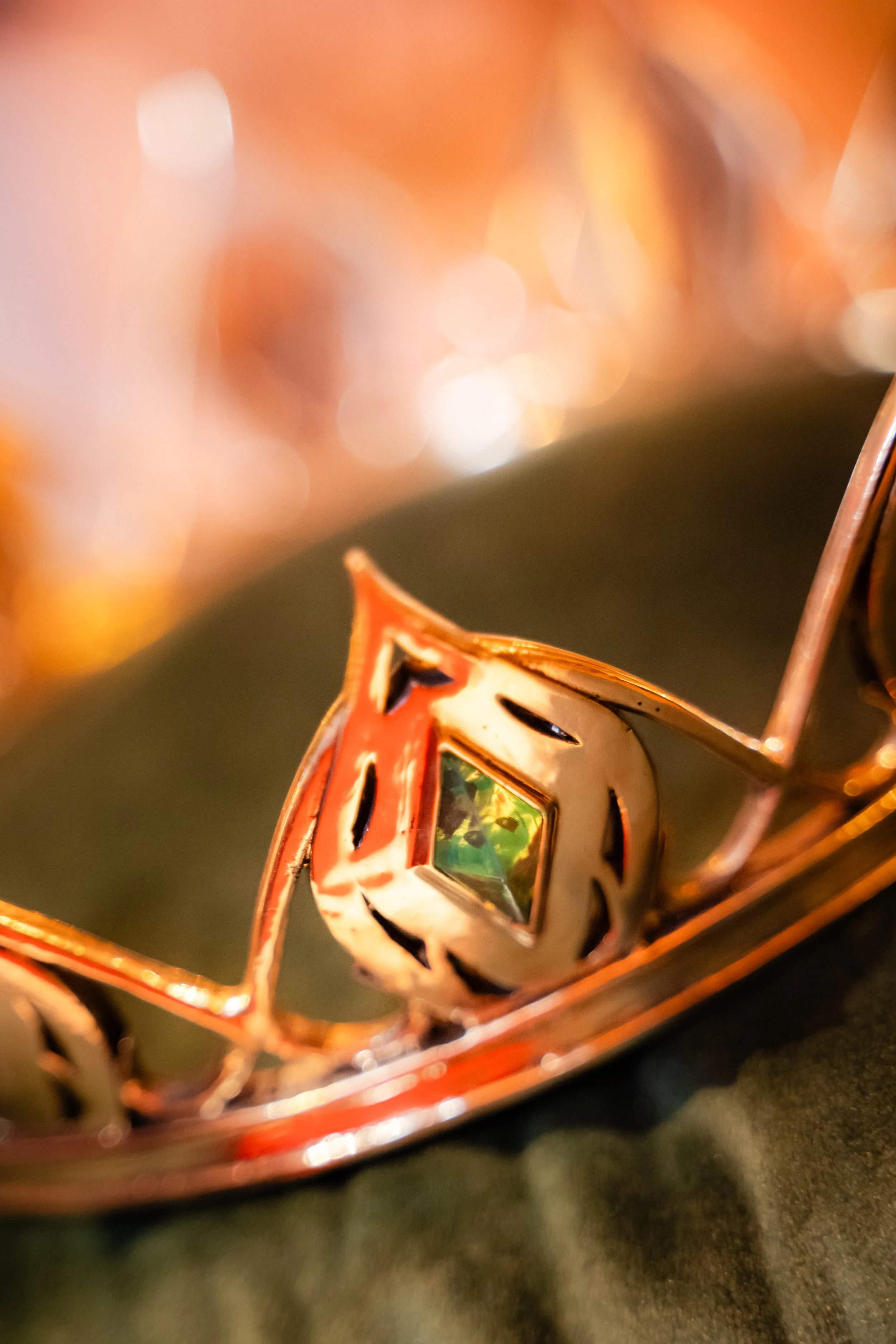 Une lampe en métal semble orange avec des motifs de fenêtres de vitrail colorées, suspendue ou posée sur une surface.