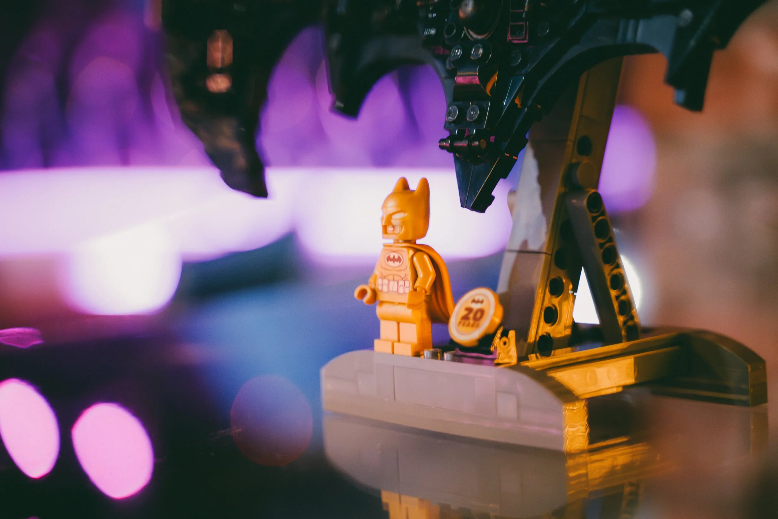 Construction de Lego Batman avec un plateau de score de 20, dans un environnement sombre avec des lumières violettes et oranges.