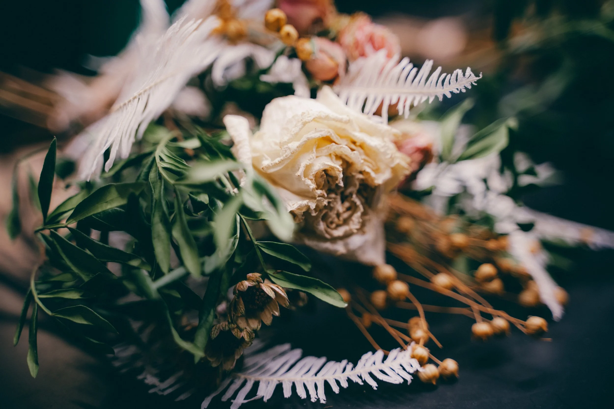 Un arrangement floral avec des fleurs séchées, des feuilles vertes et des branches, dans un style naturel et élégant.