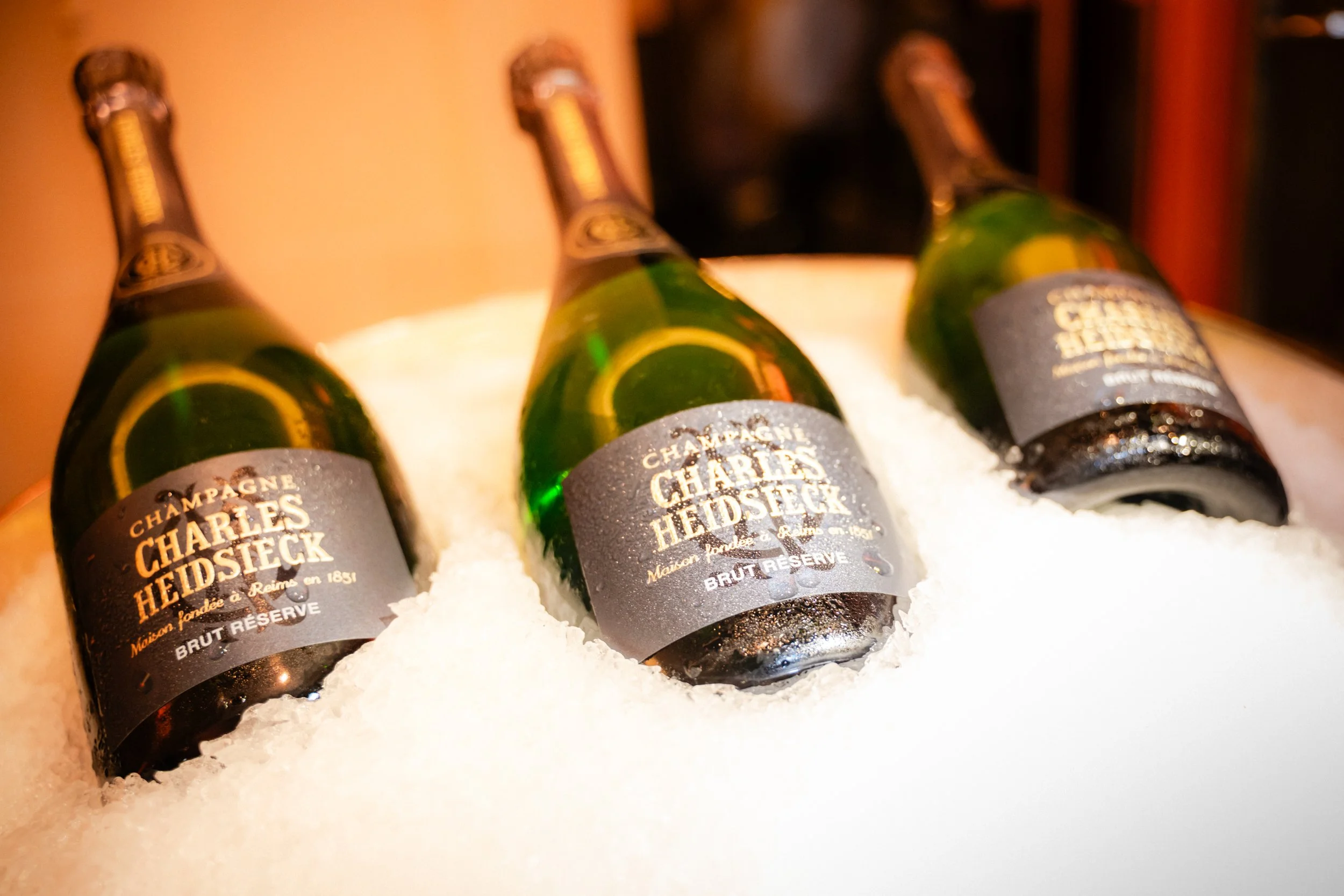Trois bouteilles de champagne Charles Heidsieck dans un seau à glace avec de la glace en dessous.