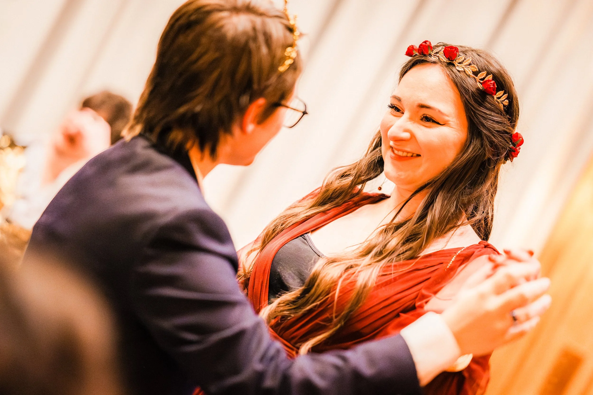 Une femme souriante portant une couronne de fleurs rouges lors d'un mariage.