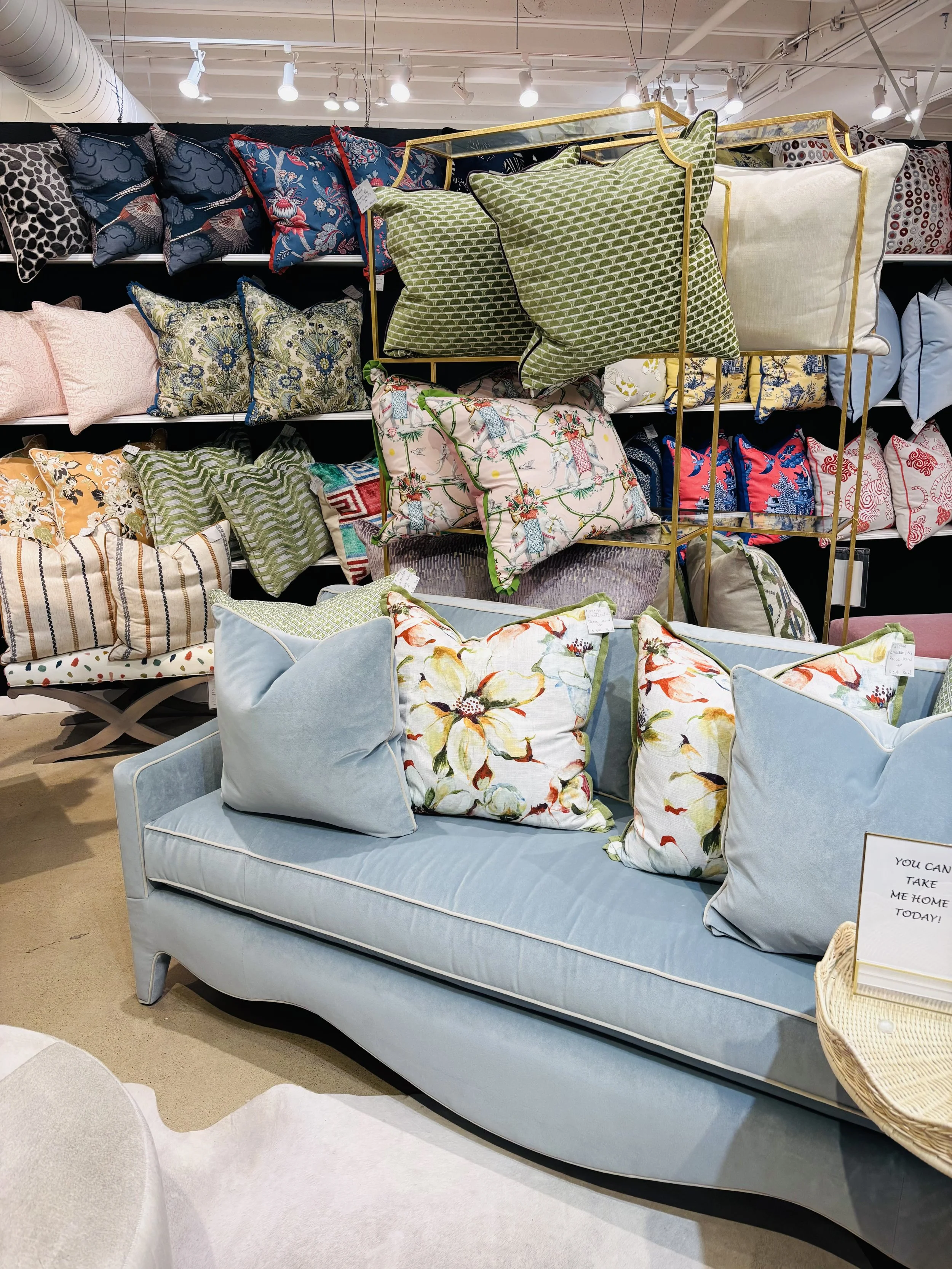 Display of various decorative pillows in different colors and patterns on shelves in a home decor store.